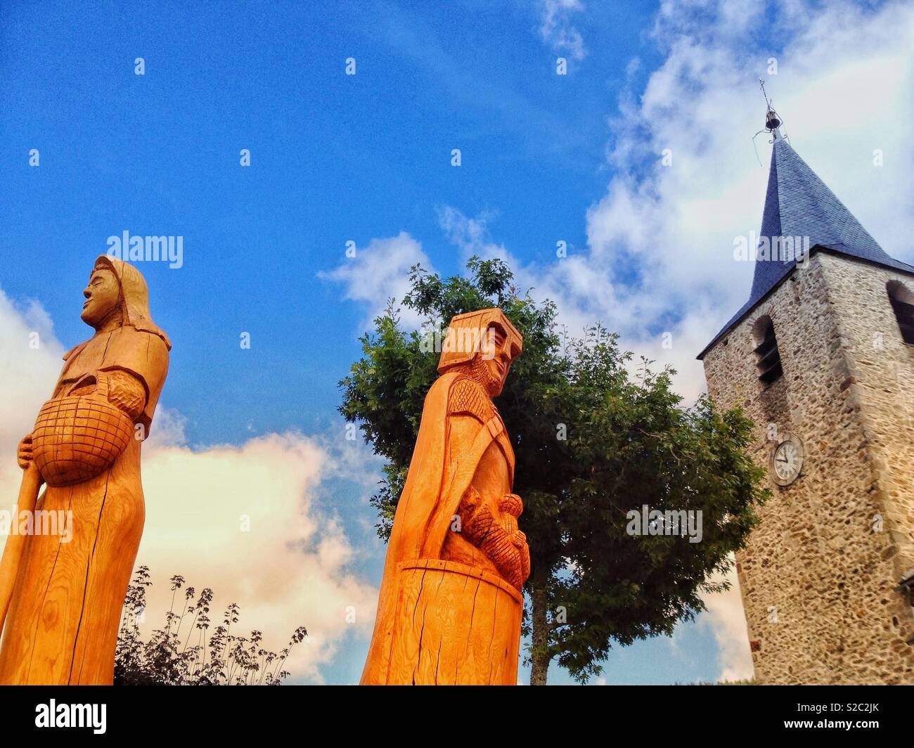 Wood sculpture and church St Victor in Nages, Tarn, Occitanie France - Smartphone Captured Stock Image