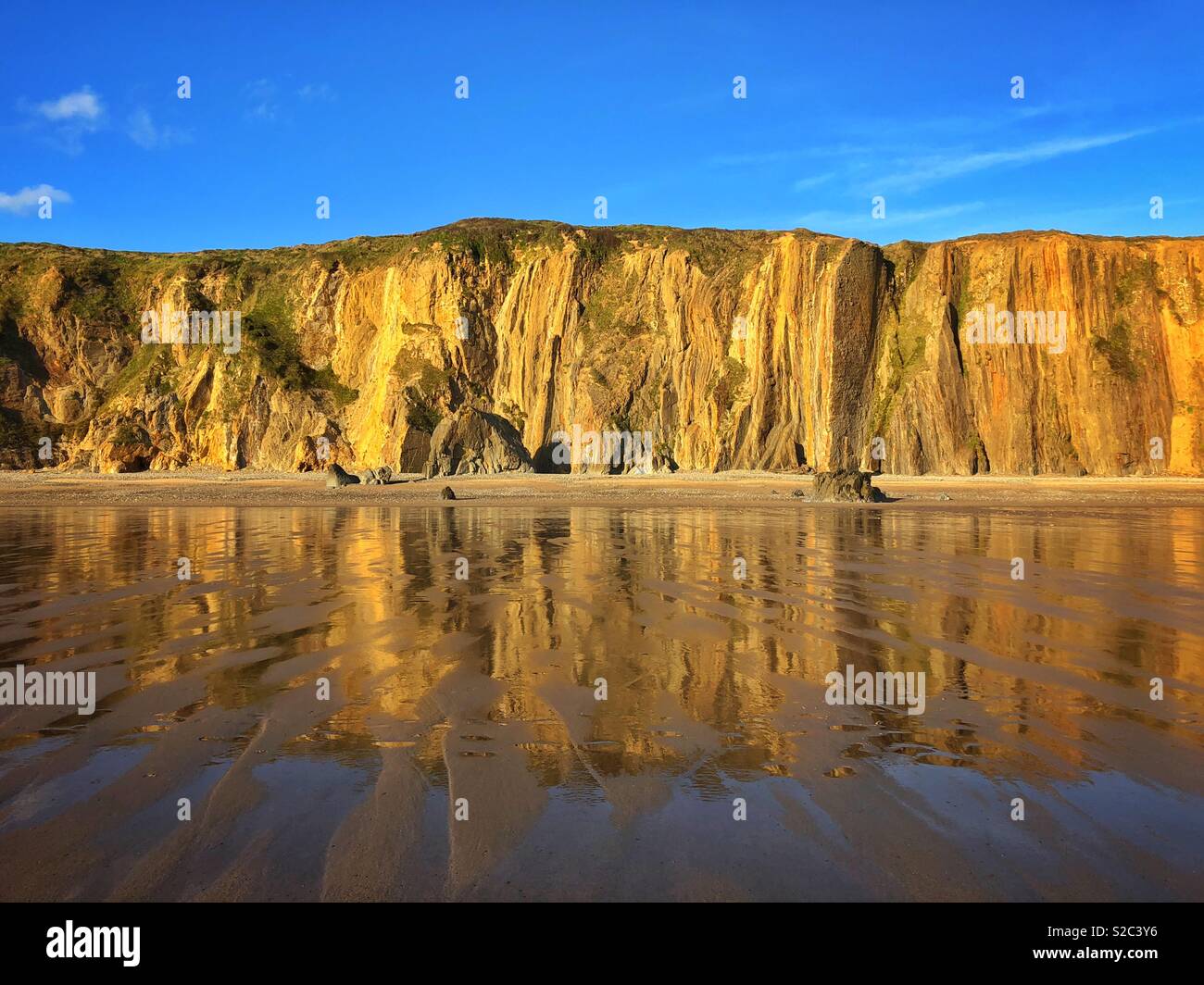 Cliffs and reflections in wet sand on  Marloes beach, Pembrokeshire, West Wales. - Smartphone Captured Stock Image