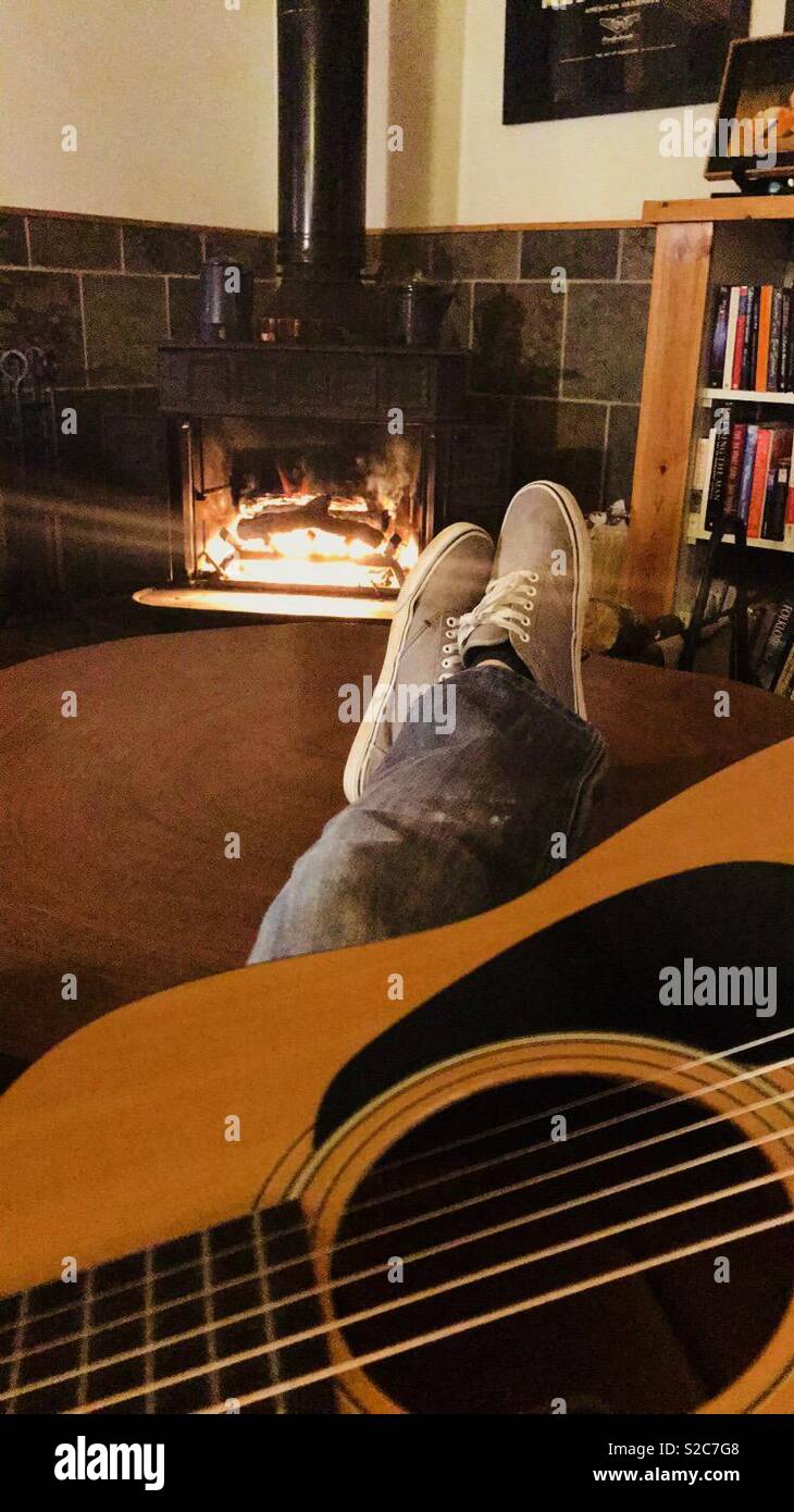 Playing guitar by the fireplace Stock Photo