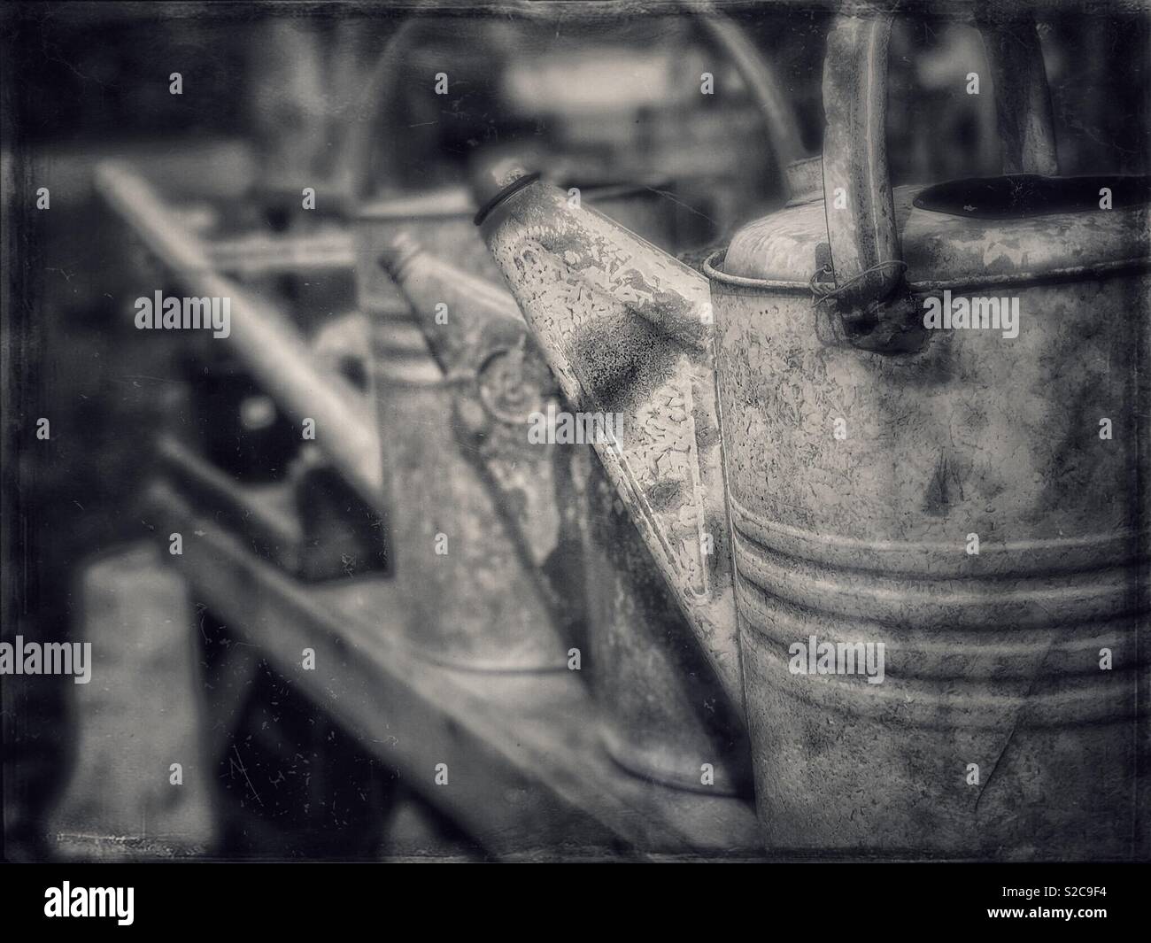 Old watering cans lined up on wooden bench - Smartphone Captured Stock Image