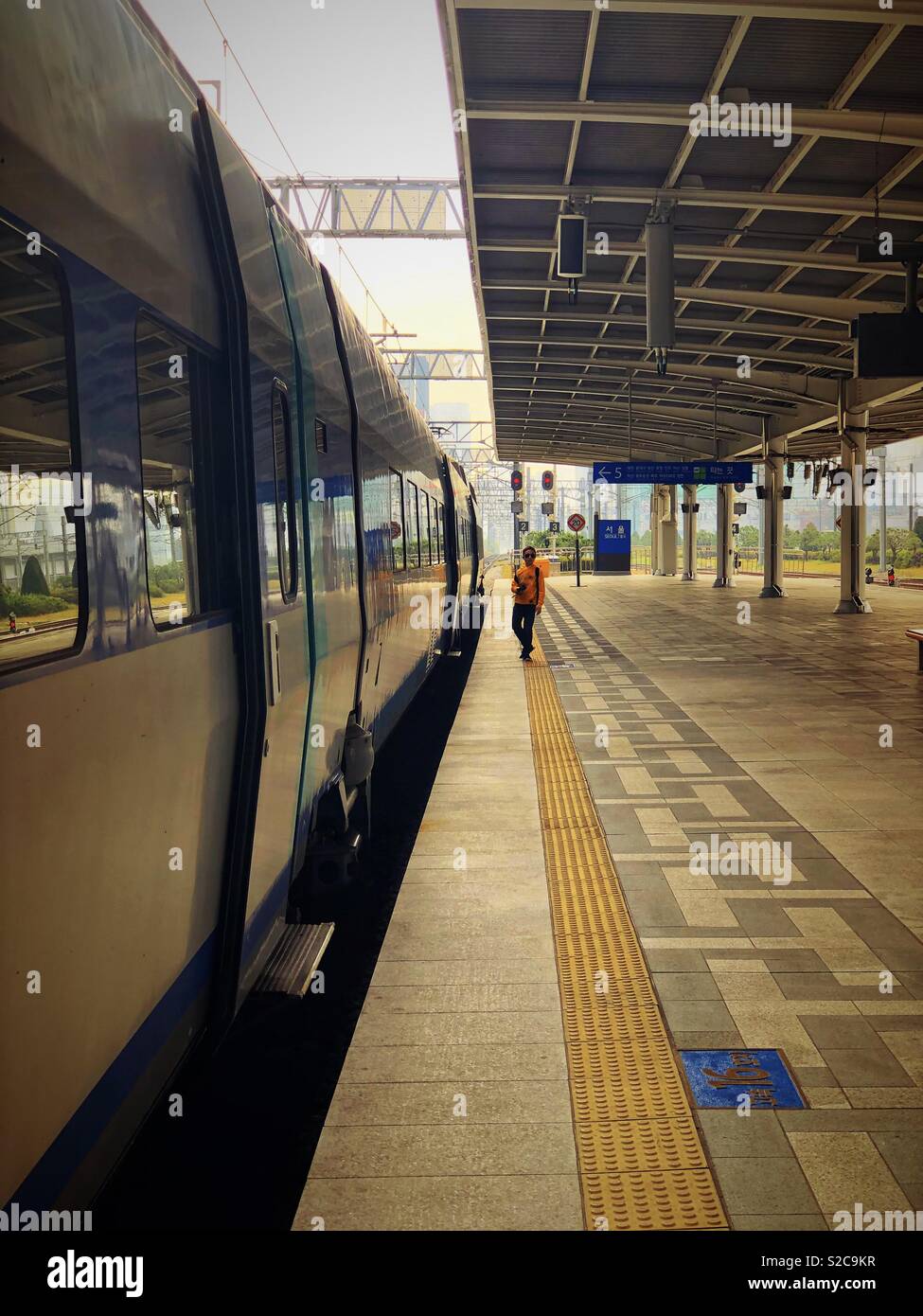 A lone figure stands next to a train on an empty platform at Seoul Station in Seoul, South Korea. - Smartphone Captured Stock Image