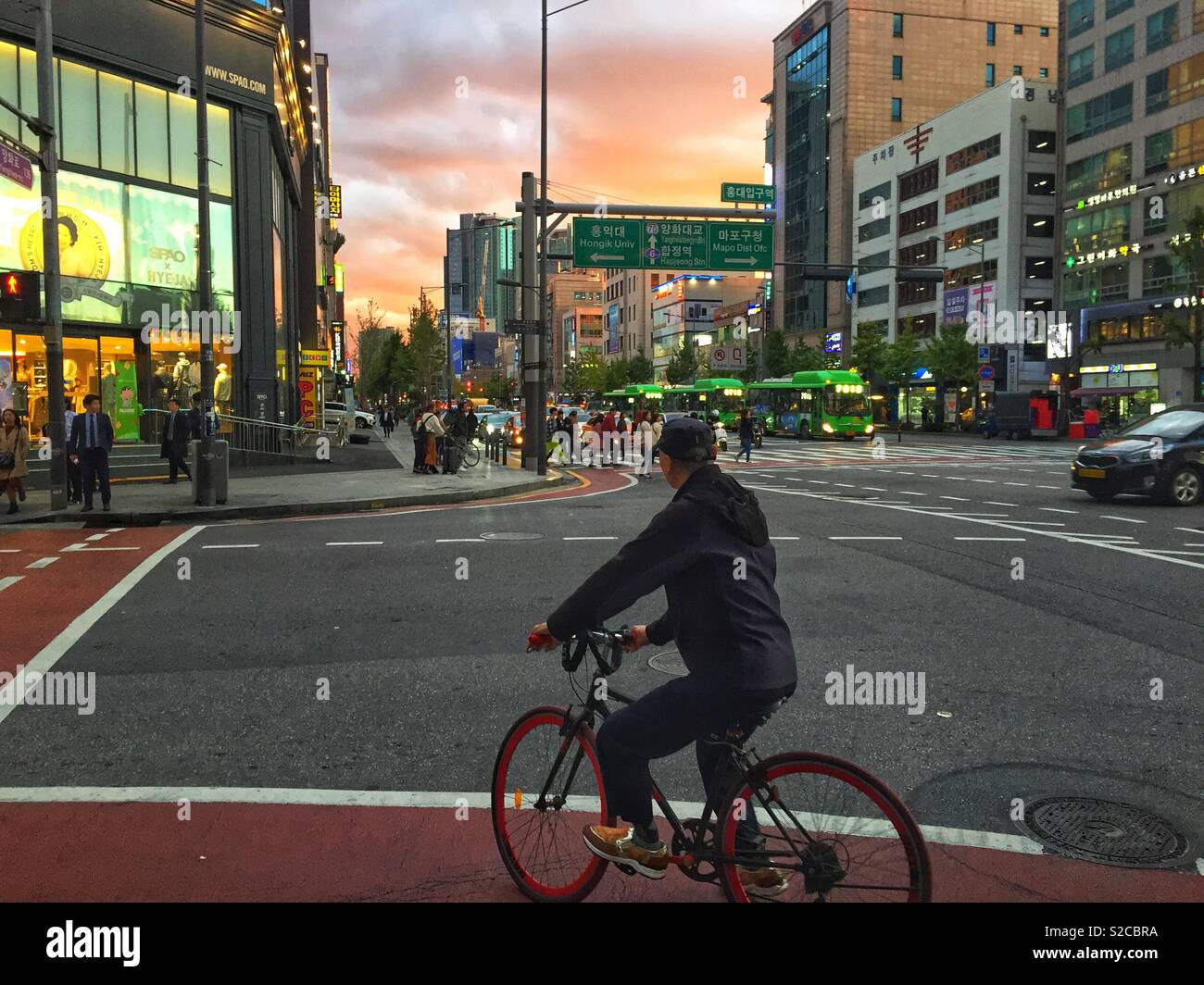 A man cycles through the busy streets of Seoul, South Korea at sunset. - Smartphone Captured Stock Image