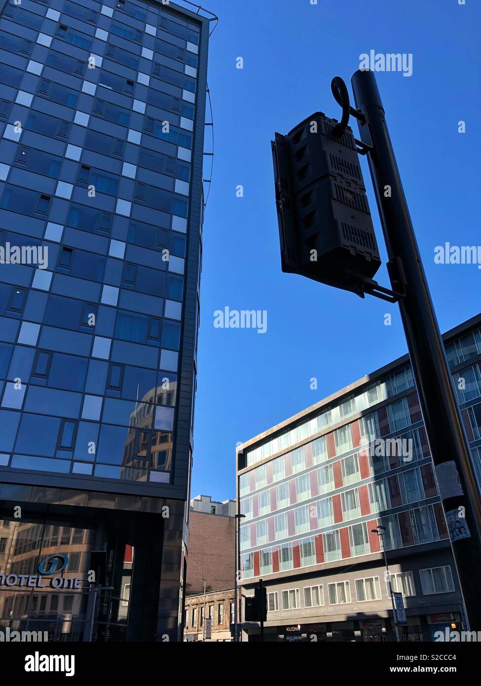 Looking up at examples of modern architecture crowded closely together in Argyle Street, Glasgow city centre, Scotland.  Traffic lights in foreground. Stock Photo