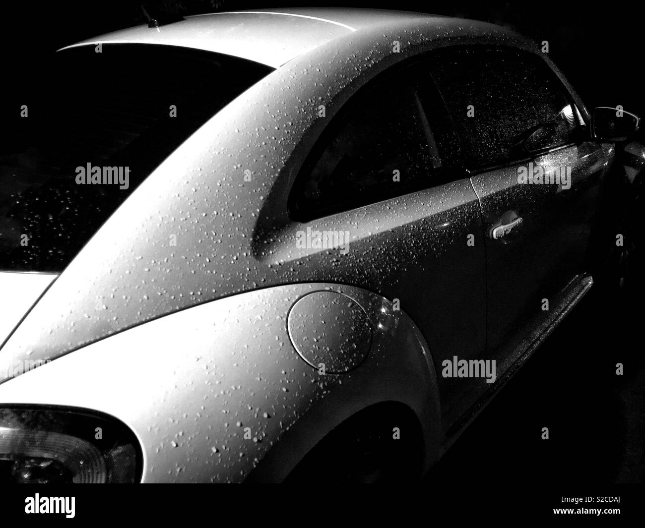 Moody black and white image of a 2012 Volkswagen Beetle covered in rain droplets - Smartphone Captured Stock Image