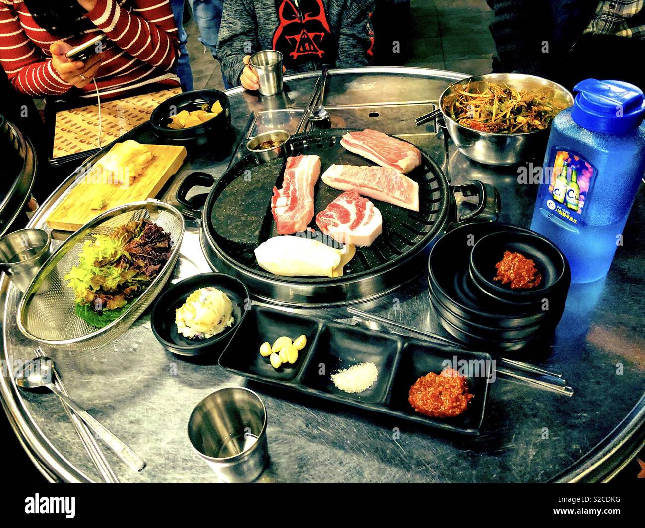 Meat starting to cook on a Korean Barbecue in a restaurant in South Korea. - Smartphone Captured Stock Image