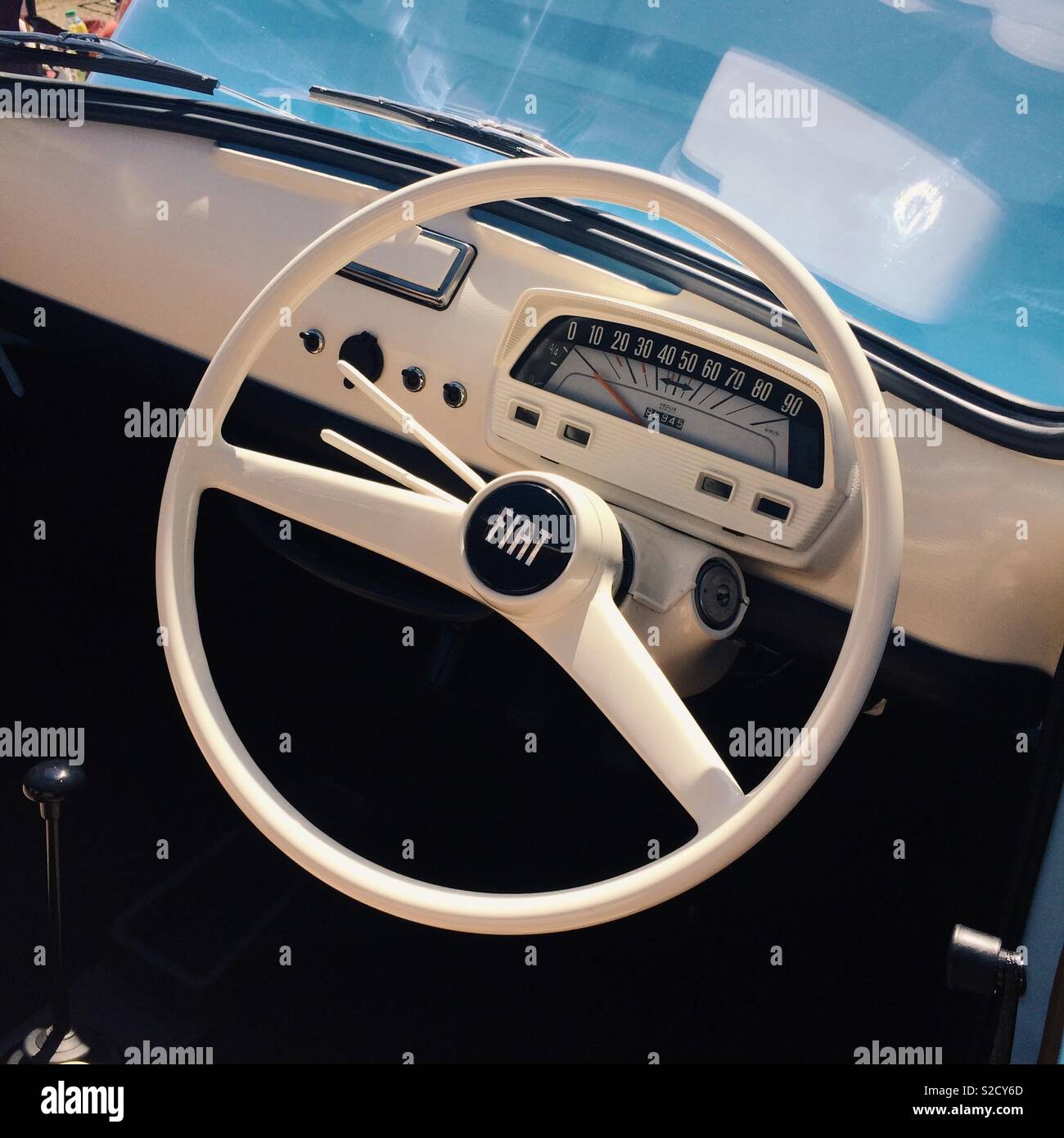A white dashboard and steering wheel interior of a retro styled fiat 500 Stock Photo