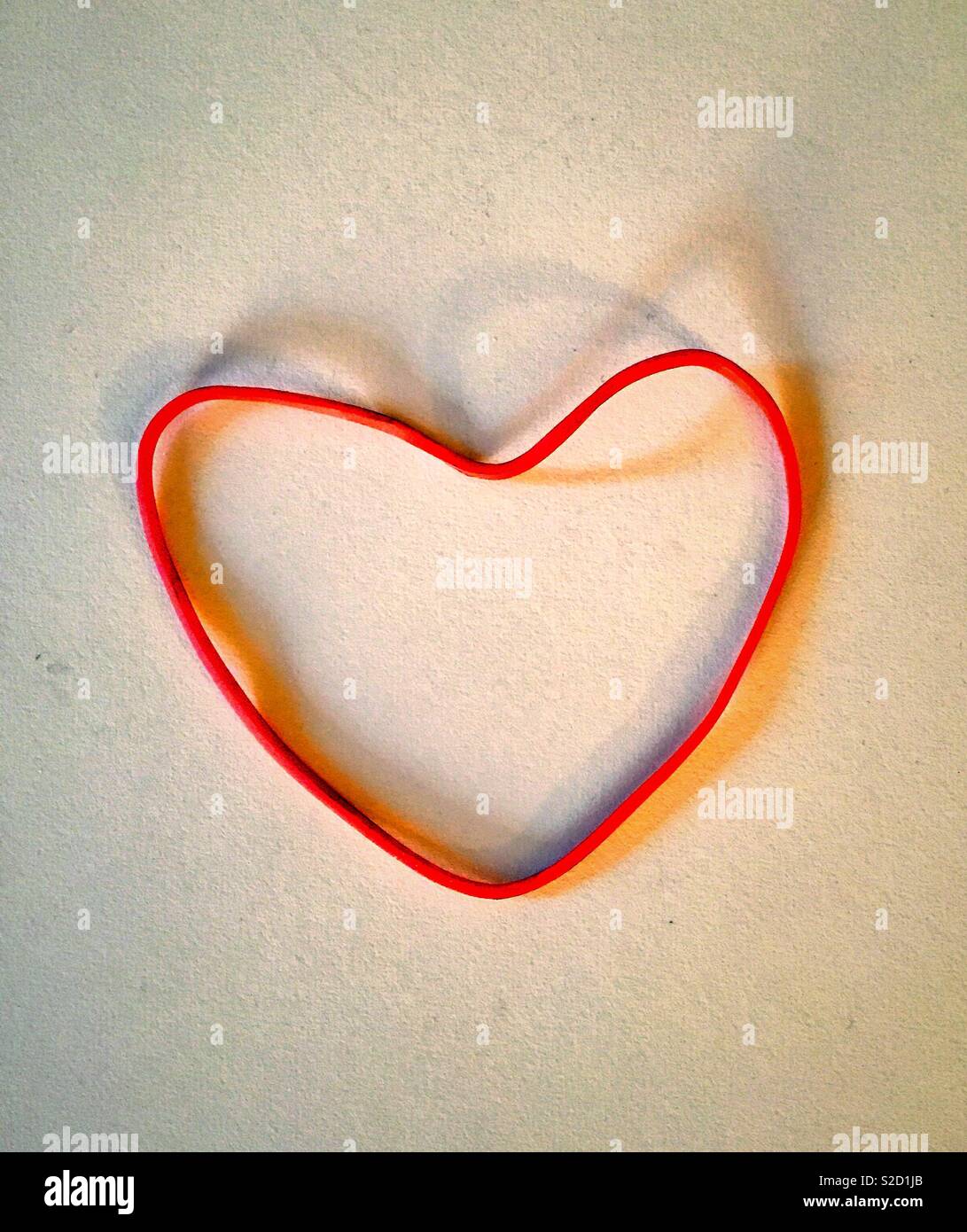Rubber band on white background in the shape of a heart. - Smartphone Captured Stock Image