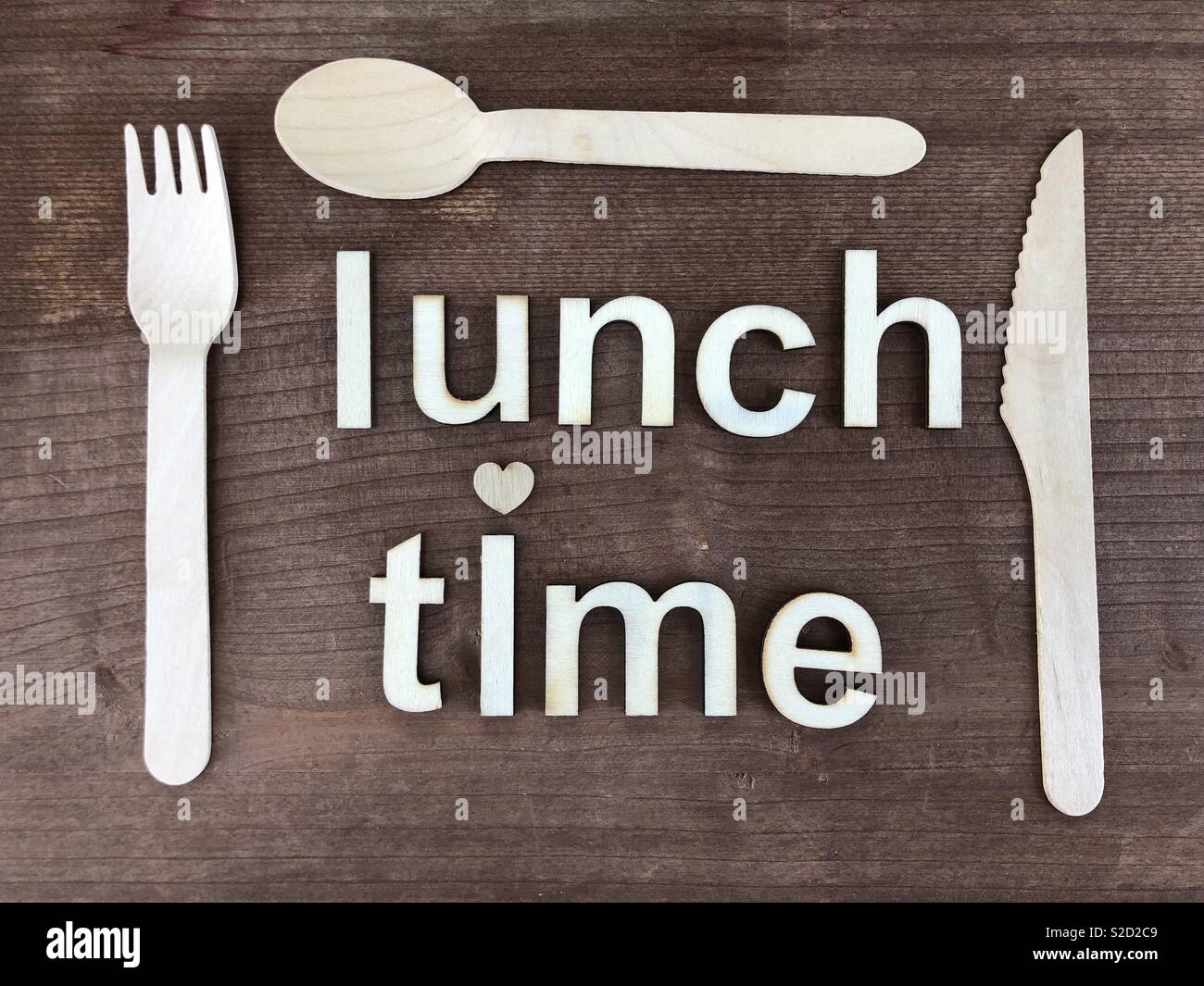 Lunch time text with wooden letters, wooden cutlery over a wooden board Stock Photo