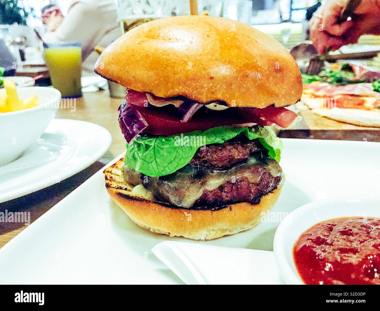 Big juicy and Tasty double half pound cheeseburger on a white plate in a restaurant Stock Photo