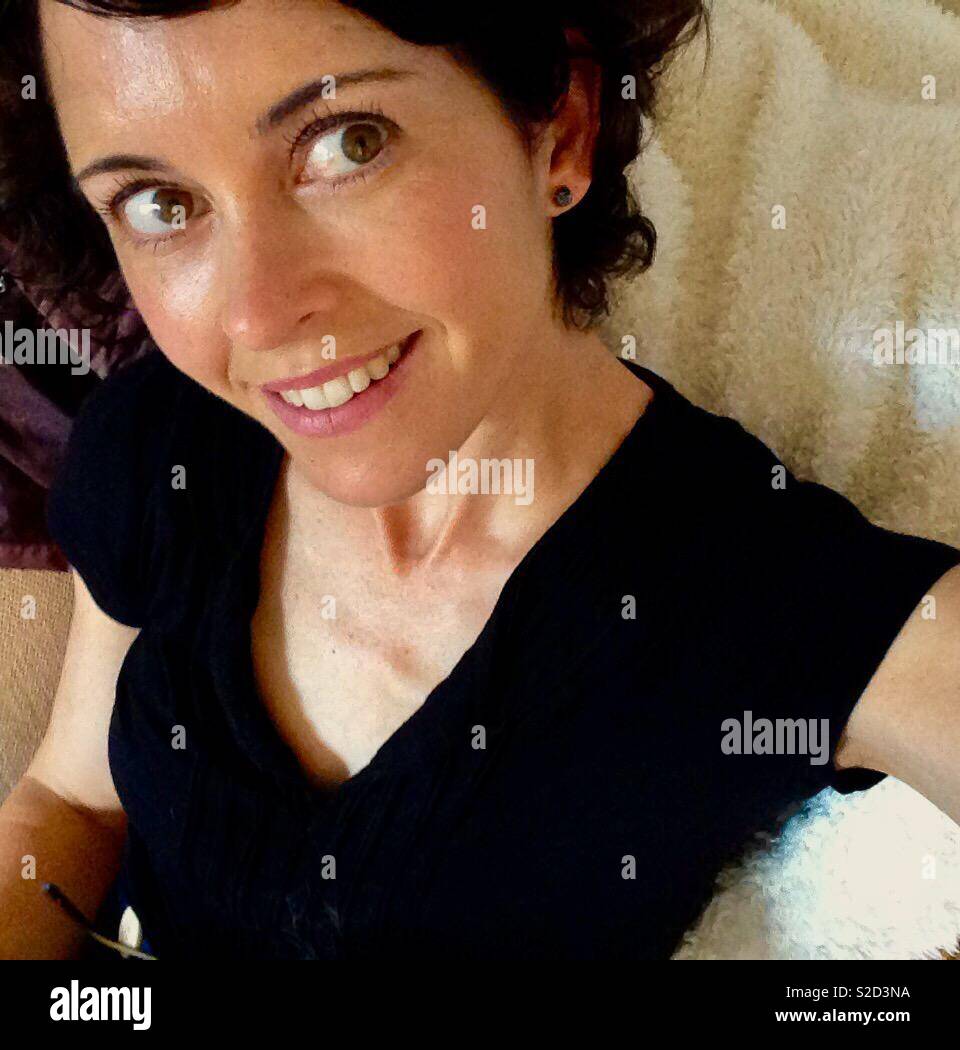 Brunette Caucasian woman in her thirties smiling - Smartphone Captured Stock Image