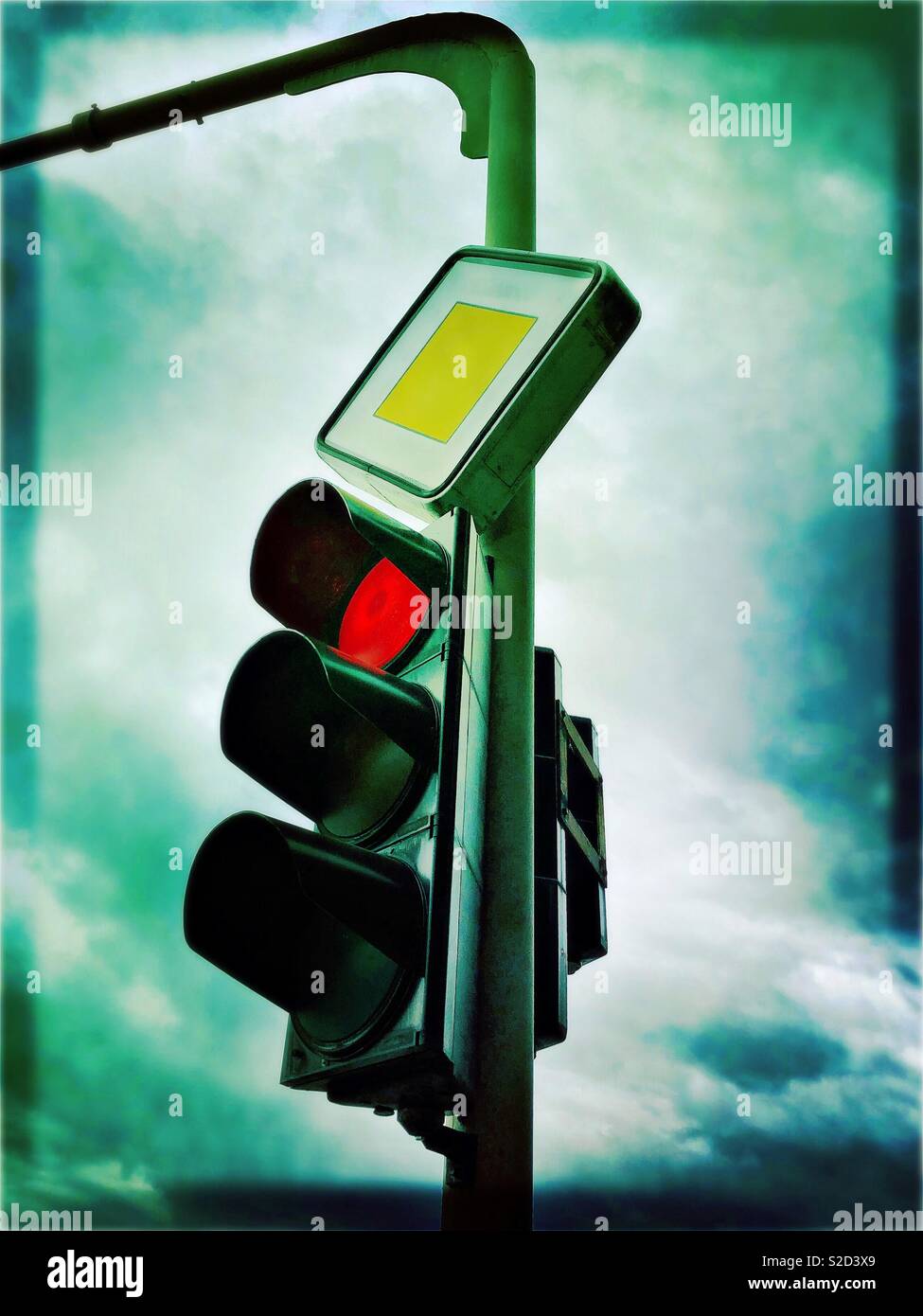 Red traffic light and main road sign on a cloudy day - Smartphone Captured Stock Image