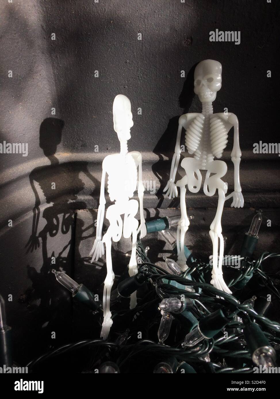 Toy plastic skeletons propped up on top of a mound of fairy lights - shadowy almost monochrome image Stock Photo