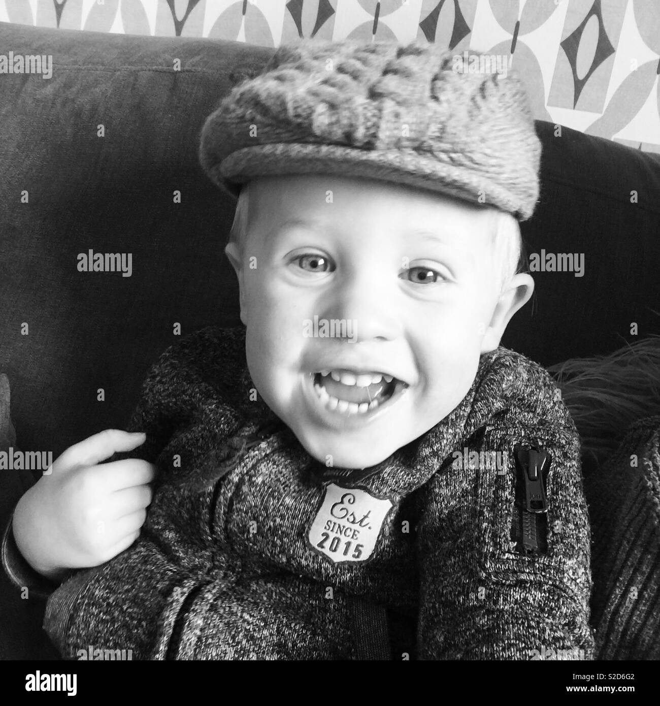 Toddler wearing flat cap smiling cheekily Stock Photo
