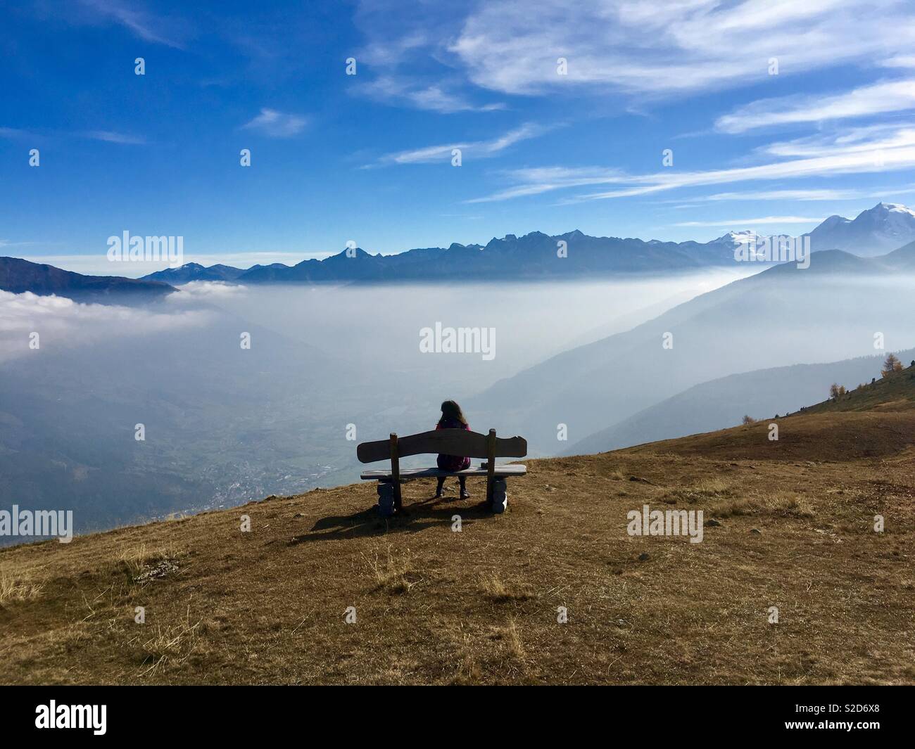 Person sitting on bench on mountain meadow at Watles, upper Vinschgau,Southtyrol, Alto Adige, Italy. Stock Photo