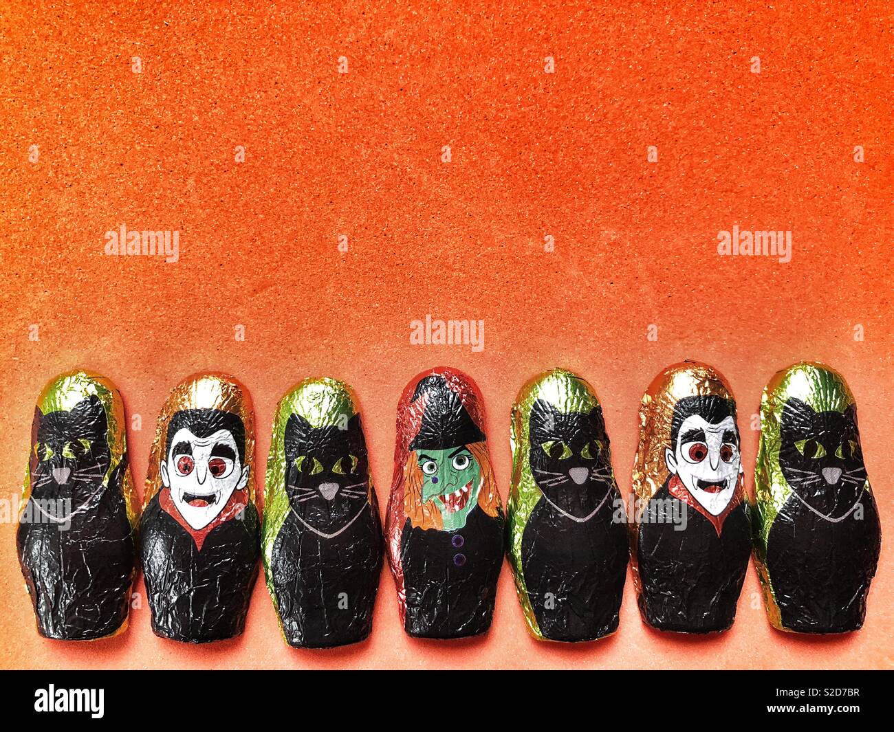 Halloween themed foil wrapped chocolates on a bright orange background - Smartphone Captured Stock Image