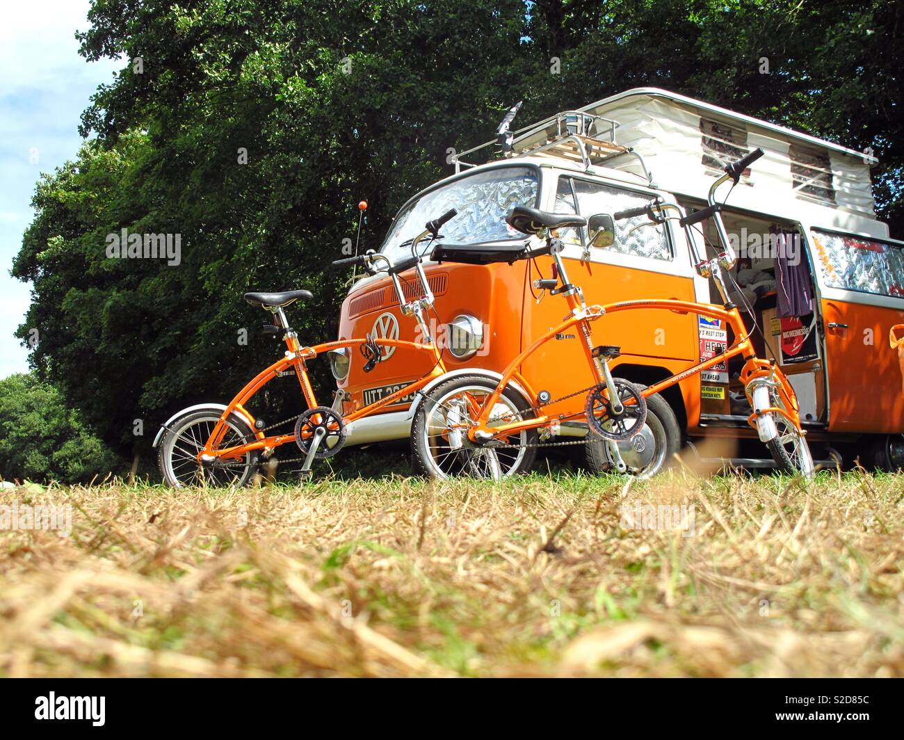 Orange Volkswagen camper van with matching retro bikes camped at tehidy woods, Cornwall Stock Photo