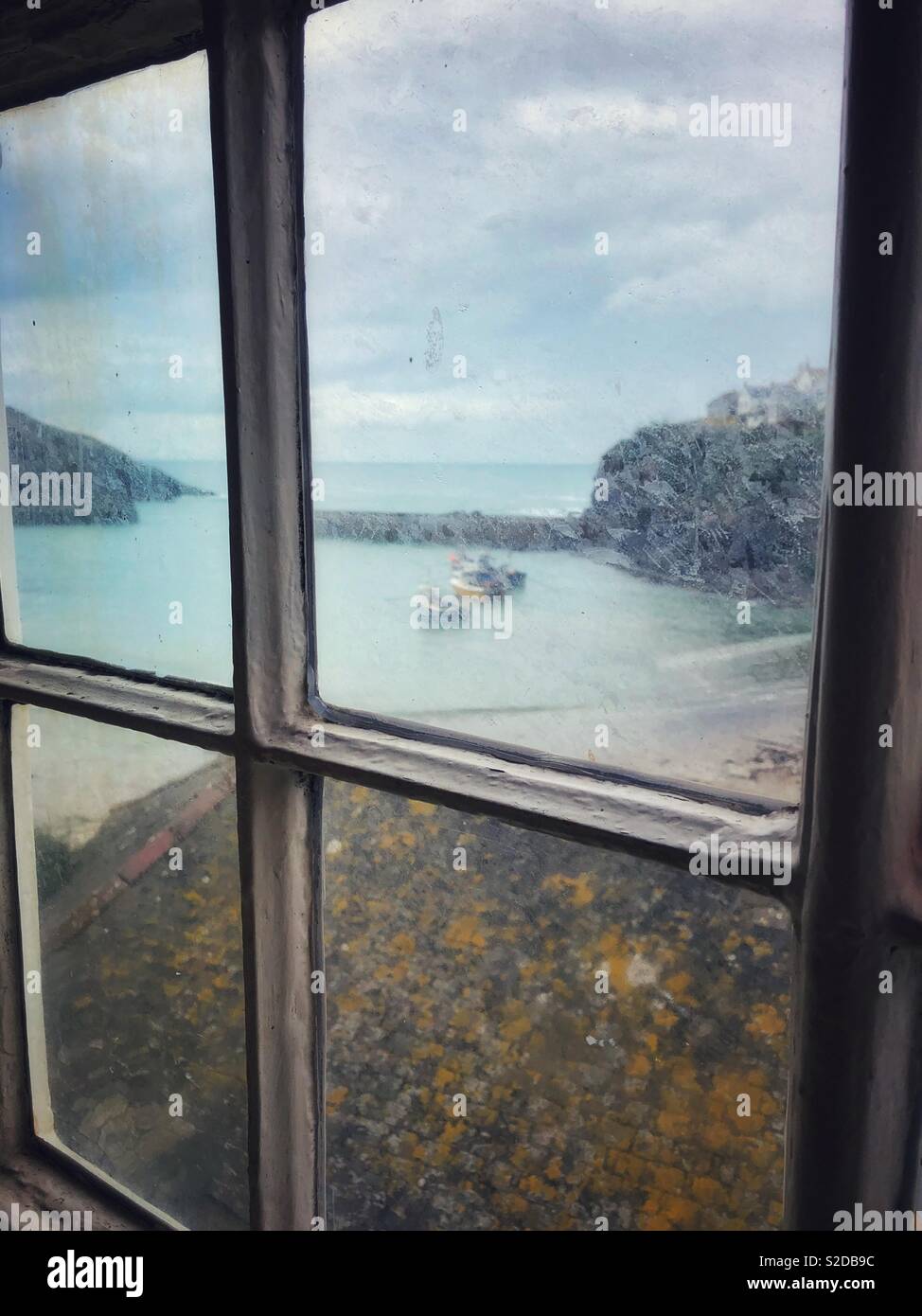 Port Isaac harbour, North Cornwall, as seen through an old upstairs window of a nearby building. - Smartphone Captured Stock Image