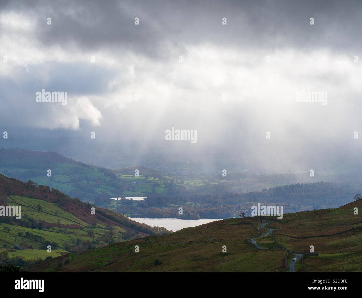 Suns rays shining on to a lake in a valley with mountains either side - Smartphone Captured Stock Image