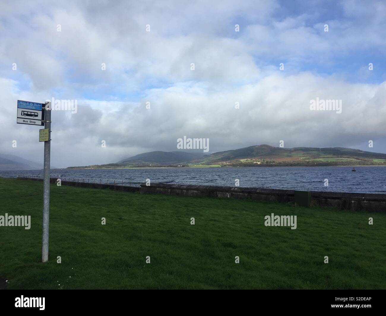 Lonely Bus stop sign in remote empty rural Scottish landscape with hills and sea Stock Photo