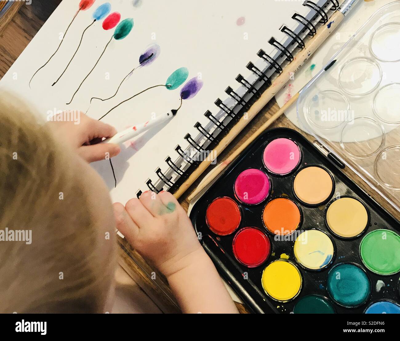 Toddler painting balloons in bright colours Stock Photo