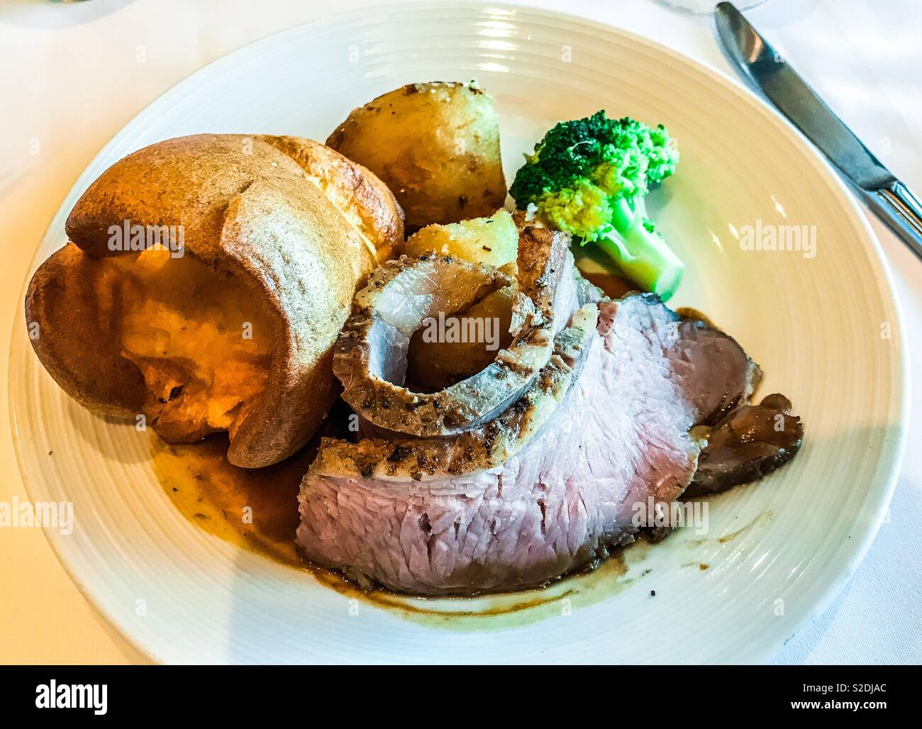 Roast beef Yorkshire pudding roast potatoes and broccoli on white plate