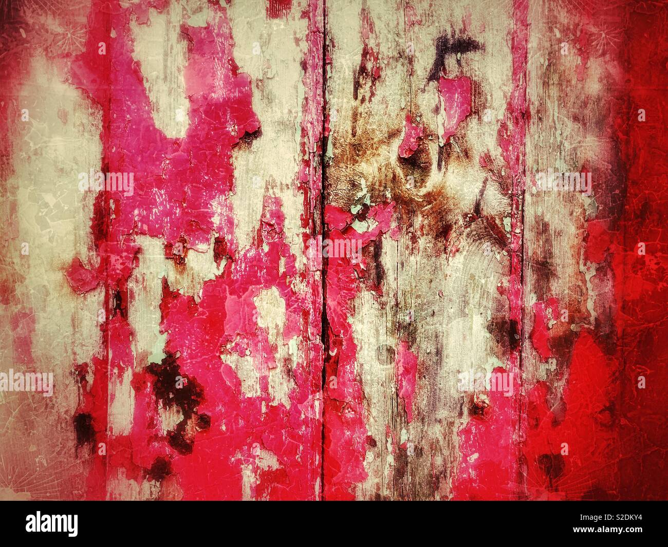 Faded peeling red paint on an old wooden door. Stock Photo