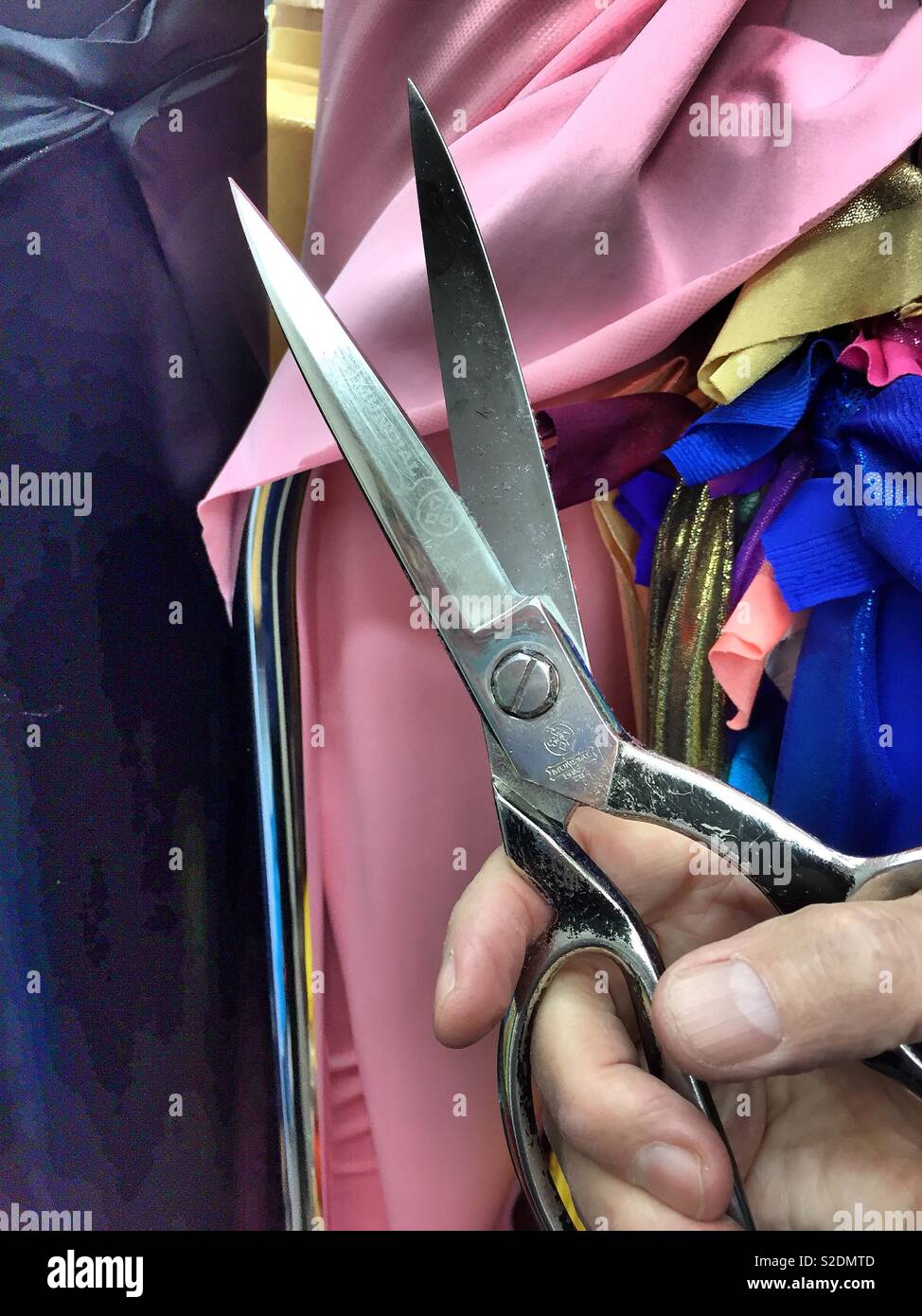 Industrial tailor’s scissors being held in front of fabric, the garment district, NYC, USA - Smartphone Captured Stock Image