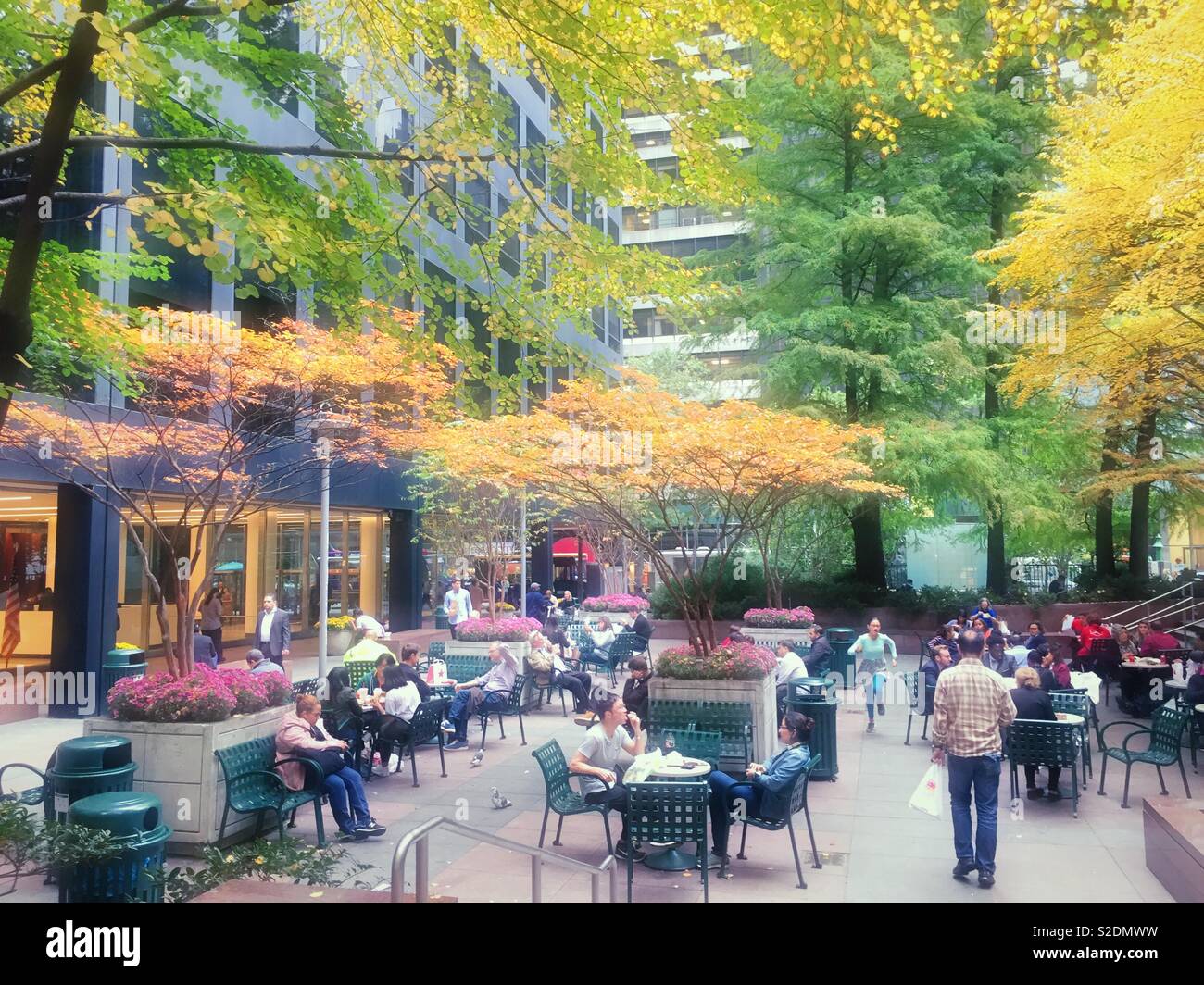 Office workers and tourists enjoying a pocket park in midtown Manhattan on a bright autumn afternoon, NYC, USA - Smartphone Captured Stock Image