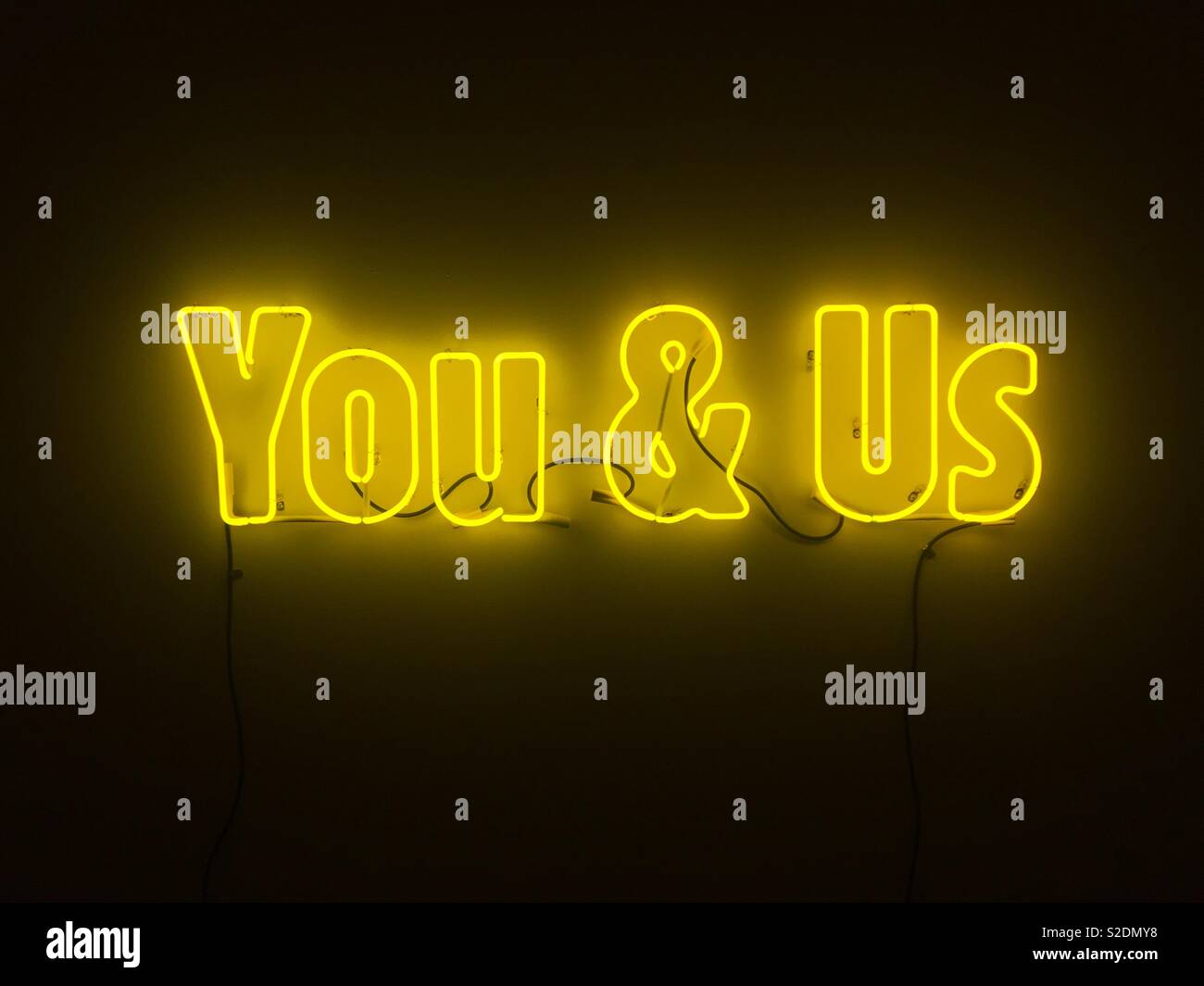 Neon yellow sign you & us - Smartphone Captured Stock Image