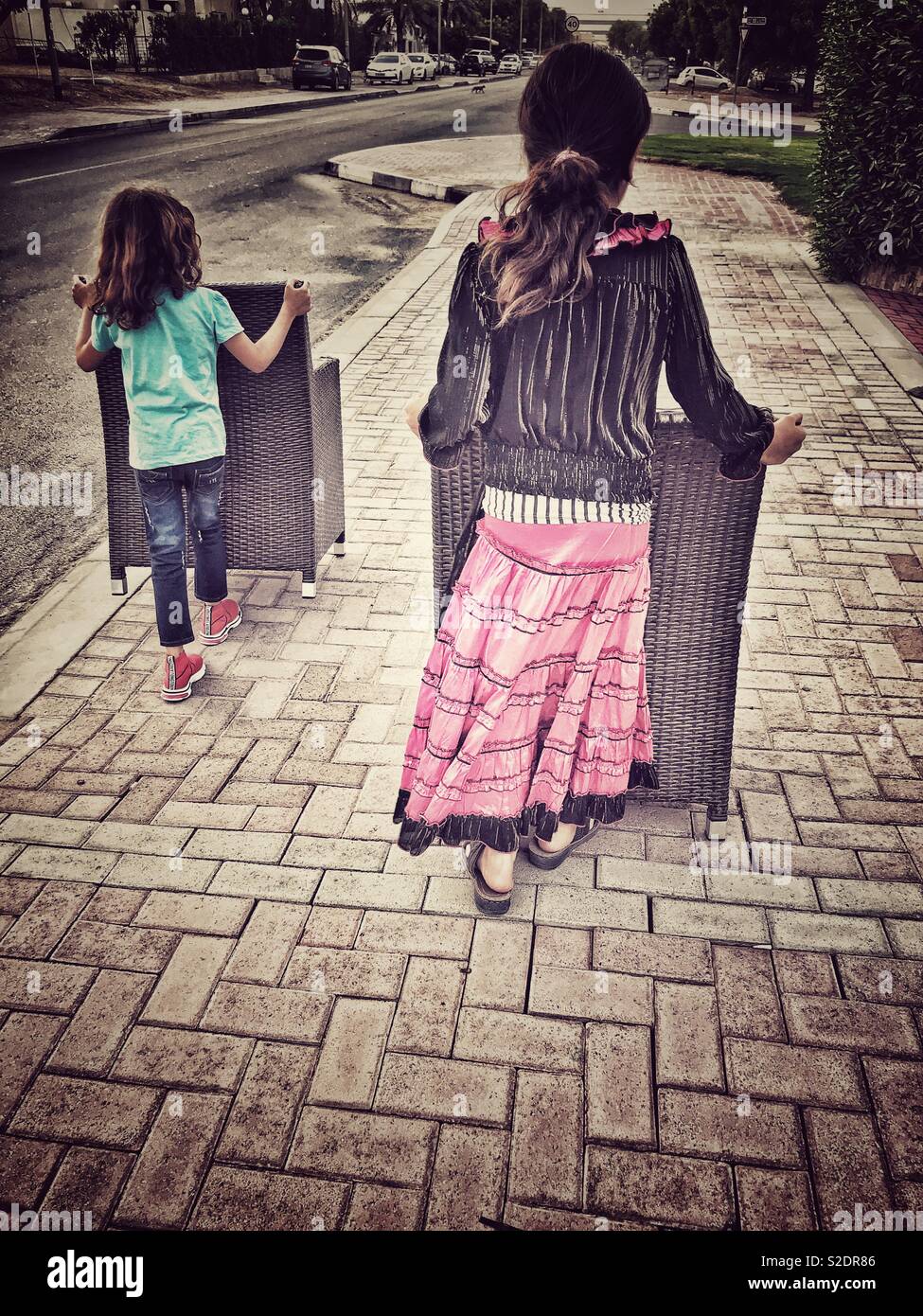 Moving: two girls moving chairs along the street - Smartphone Captured Stock Image