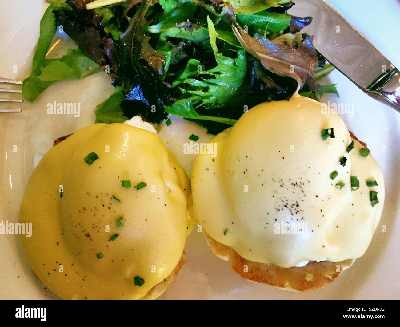 Entrée of eggs Benedict with a side salad served at eight French bistro for lunch, Soho, NYC, USA - Smartphone Captured Stock Image