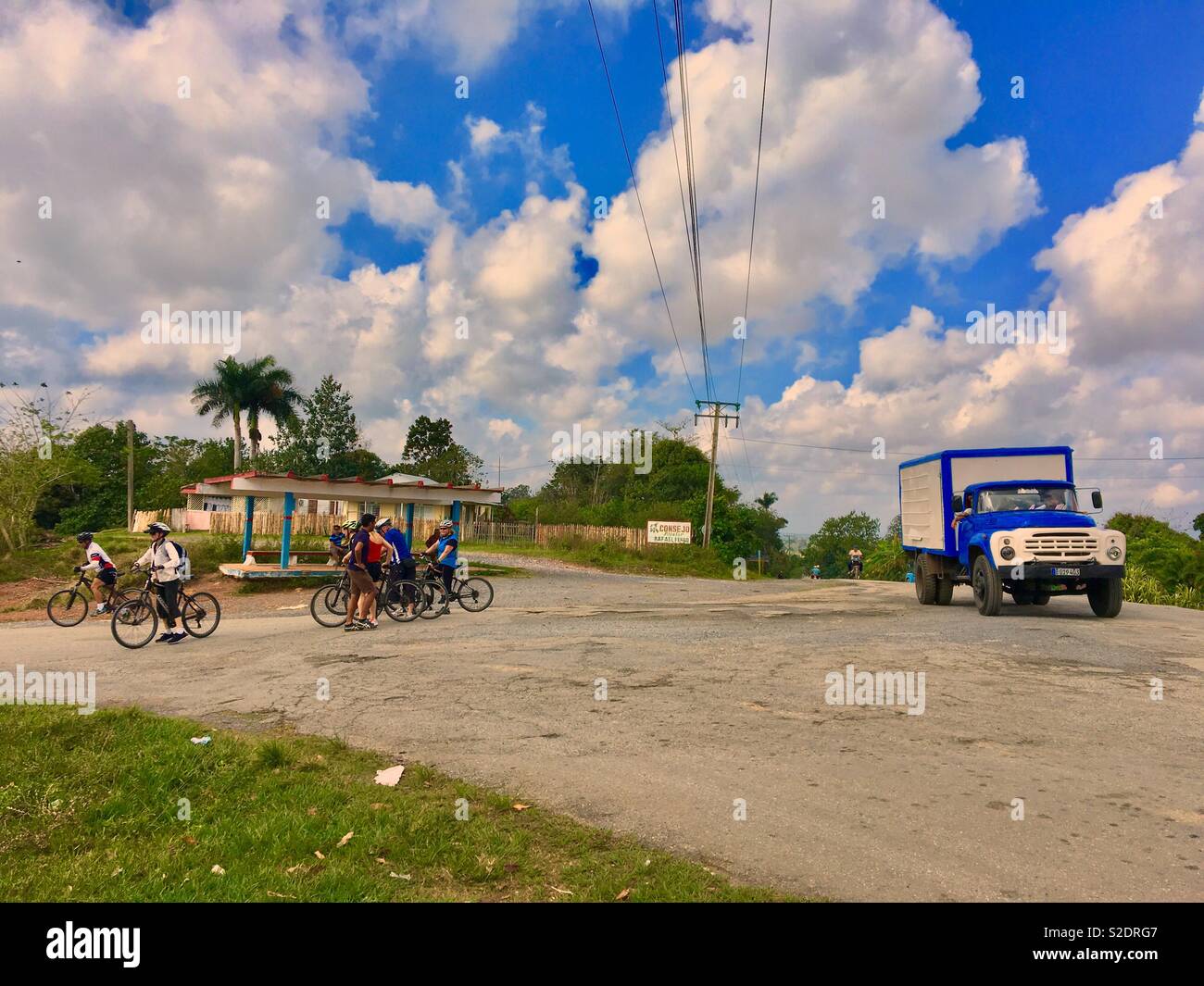 Tourists on a bicycle tour in Viñales Cuba with local Cubans passing in a old vintage truck Stock Photo