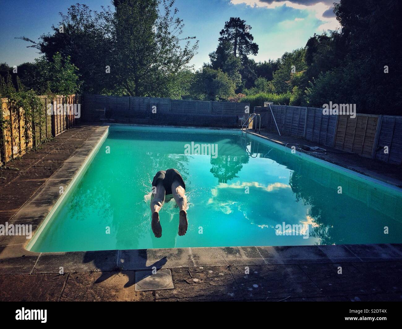 A man dives into a small, private open air pool in rural England Stock Photo