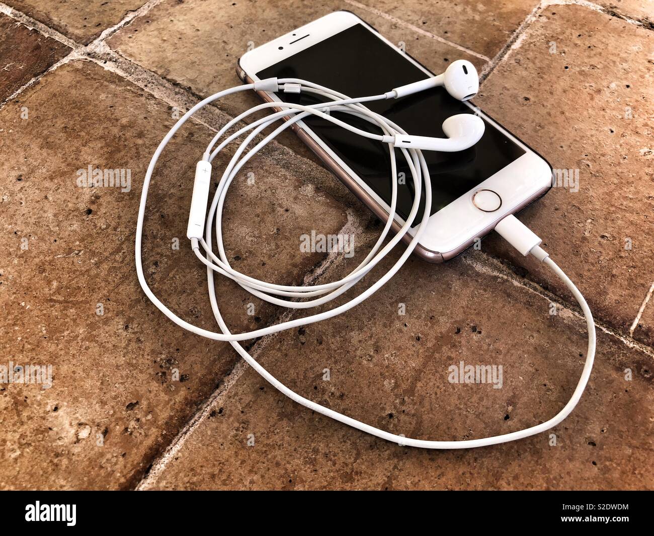 Smartphone and earphones on terracotta tiled floor Stock Photo