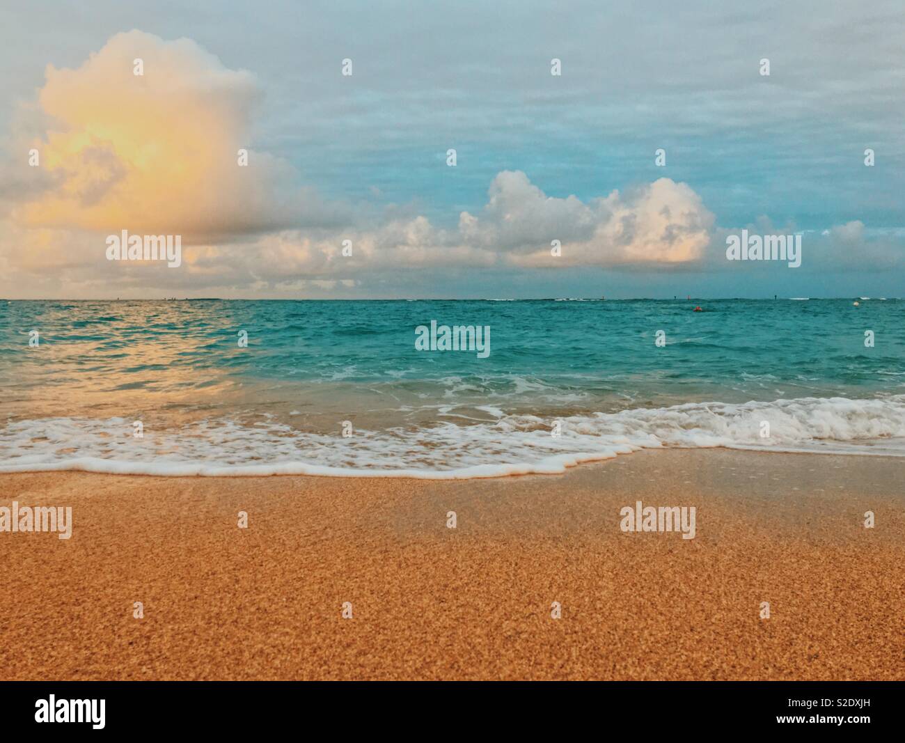 Seascape of gentle wave washing up onto sandy beach on a sunny early morning. Space for copy. - Smartphone Captured Stock Image