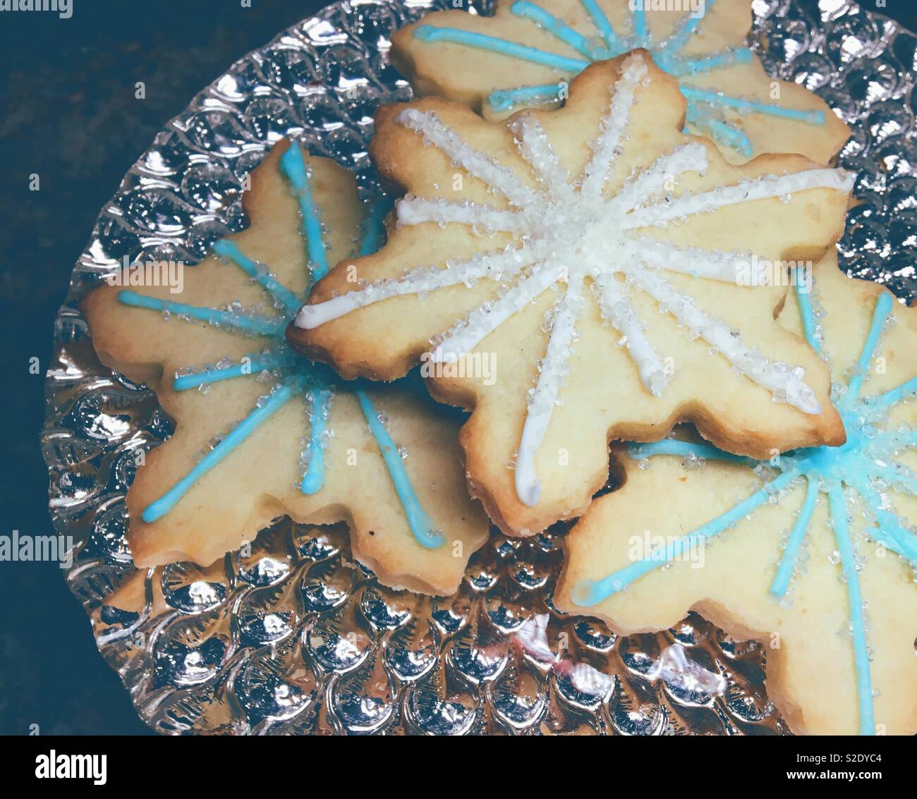 Close up of decorated snowflake shaped Christmas cookies on a silver platter. - Smartphone Captured Stock Image