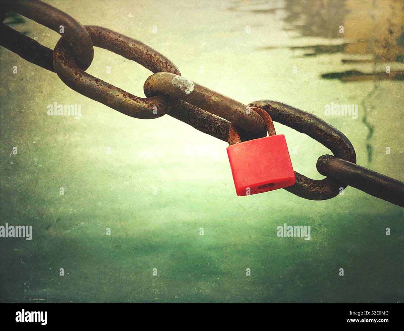 Red padlock or love lock on the rusty chain by the sea - Smartphone Captured Stock Image