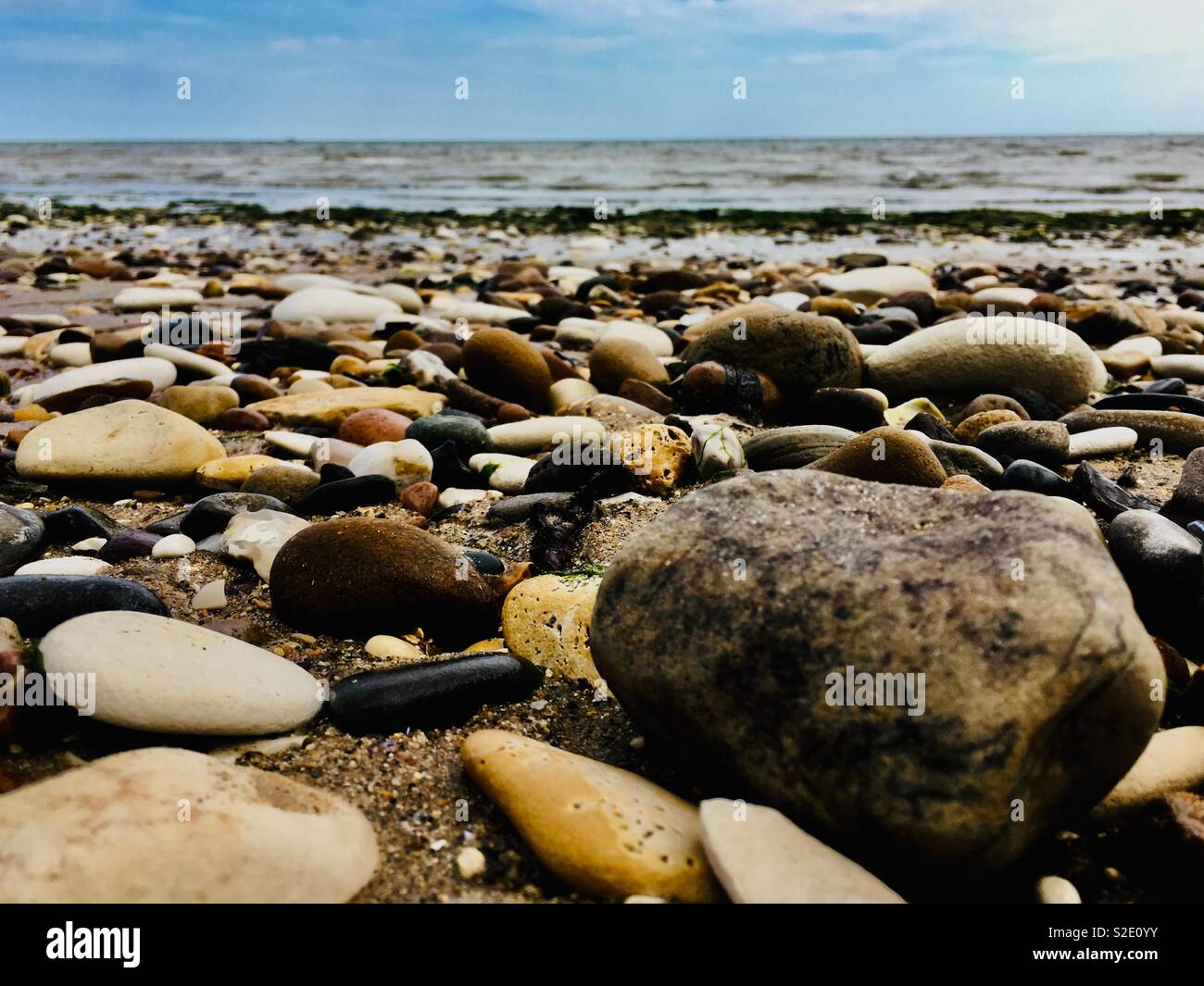 Looking out to sea over cobblestones on a beach Stock Photo