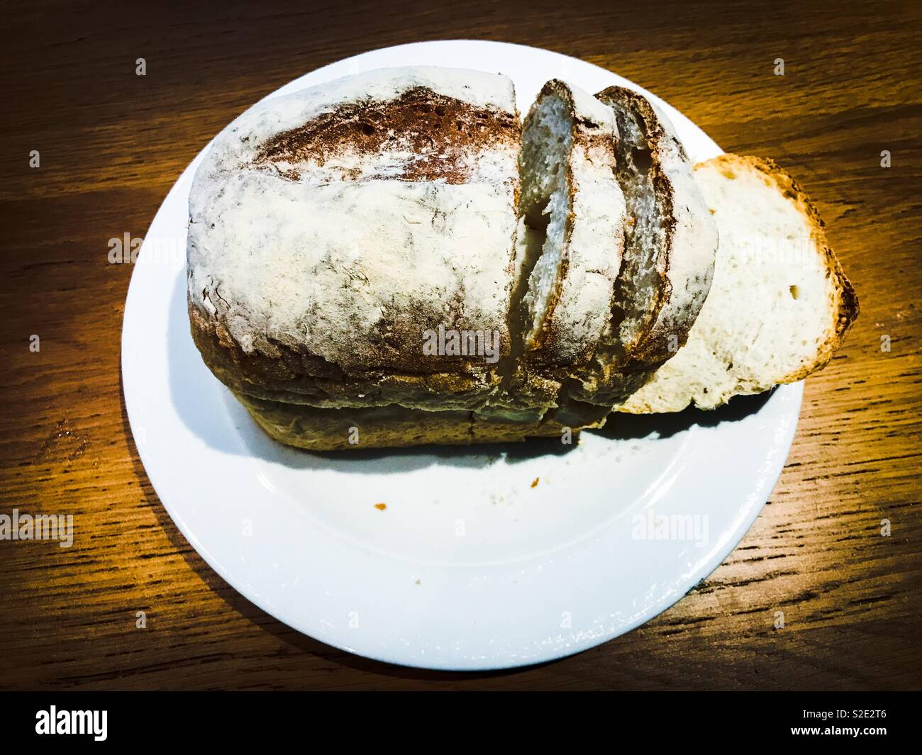 Loaf of white bread sliced on a white plate Stock Photo