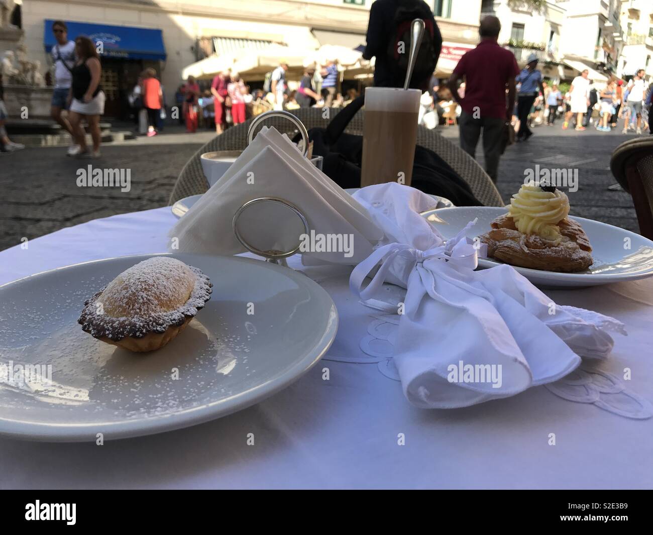 The Sfogliatella Santa Rosa pastry with cream on top accompanied by another pastry at the front and latte at the back. At the Andrea Panza Cafe in Amalfi, Campania, Italy. Stock Photo