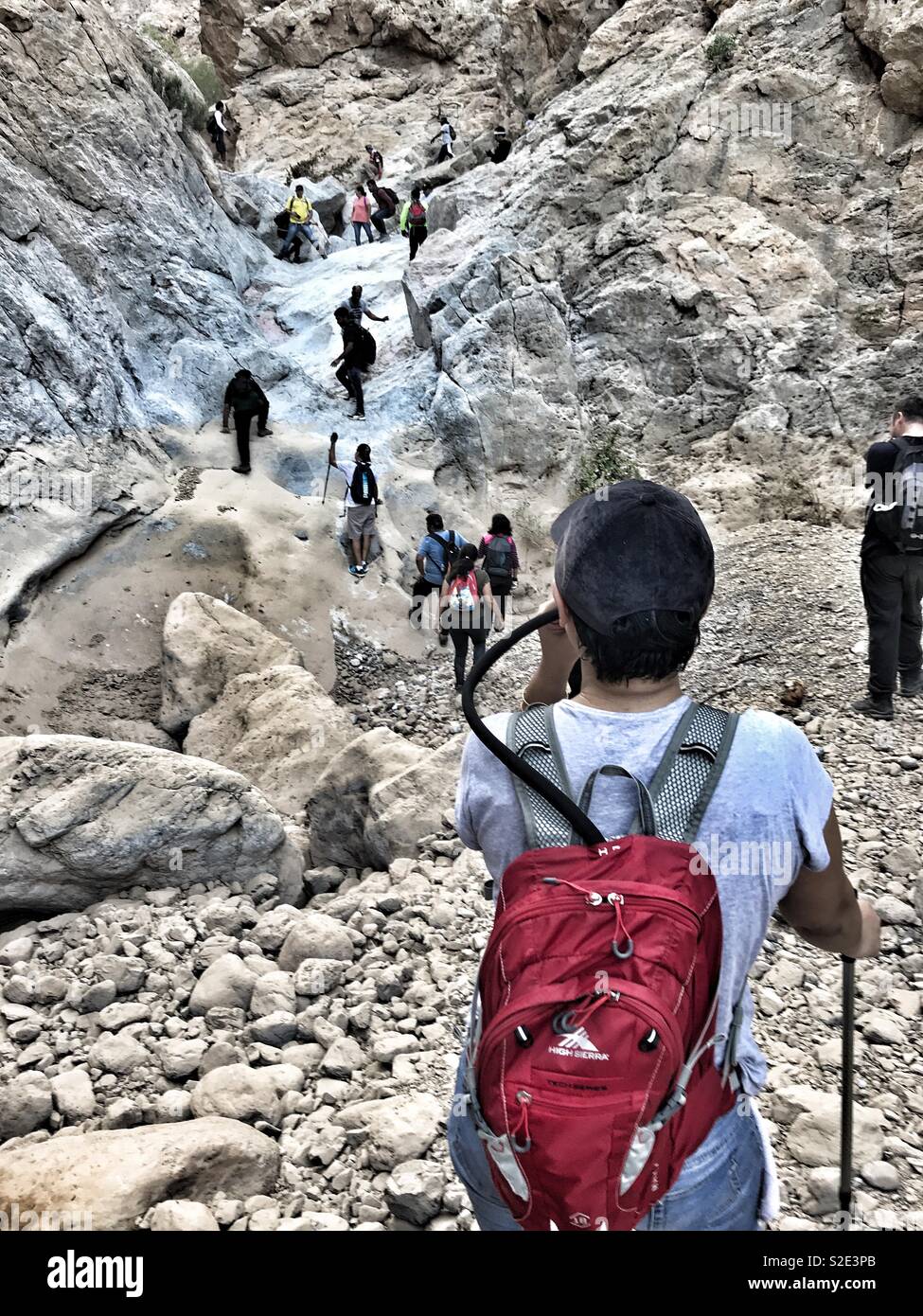 Weekend activity -tracking and hiking in Oman. A tracker is drinking from a camel back bag - Smartphone Captured Stock Image