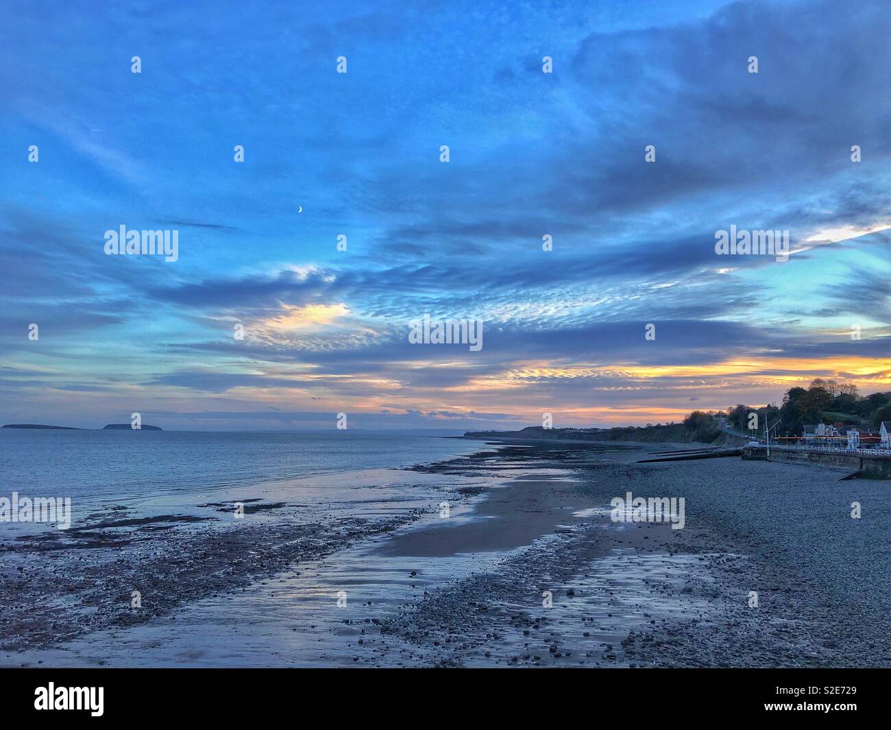 Penarth beach at dusk under a crescent moon, with Flatholm and Steepholm islands in the distance, November. Stock Photo