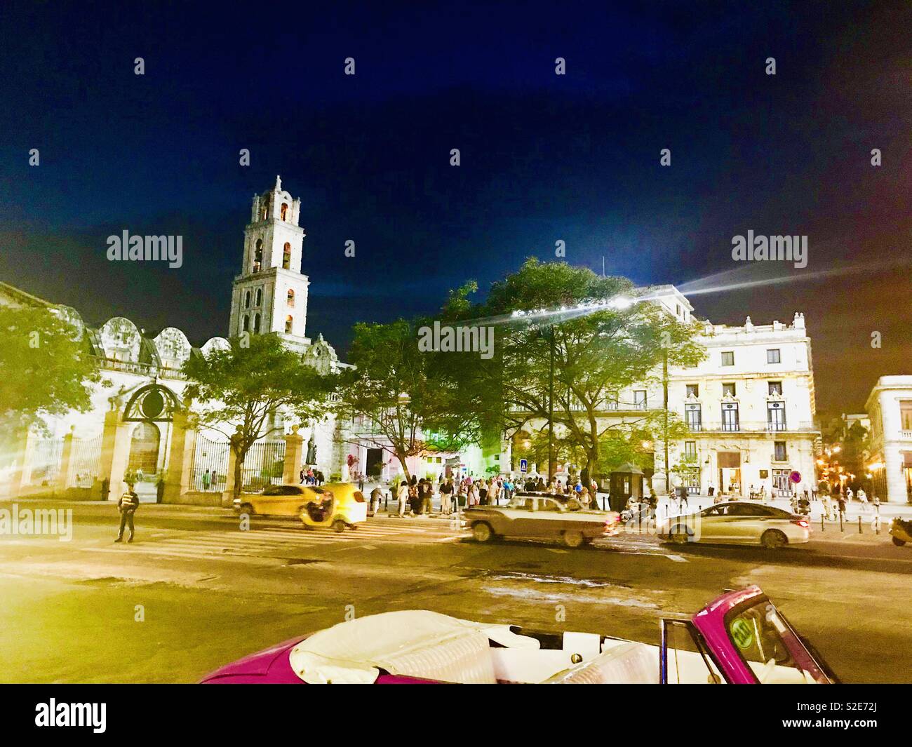 Church and convent of St.Francis, square with restaurants and bars at night, classic cars driving past, Havana Cuba Stock Photo