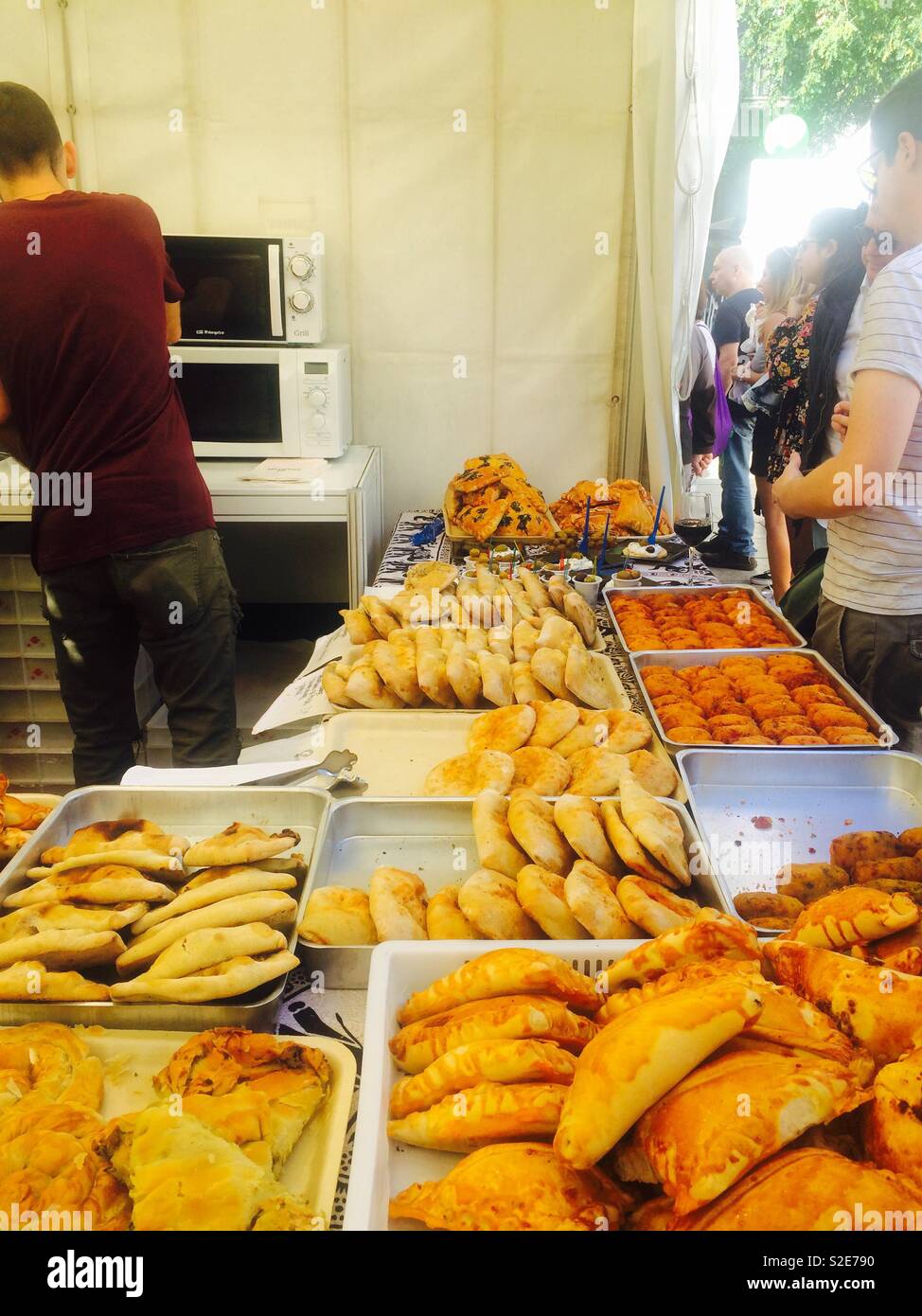 Warming up food in a microwave for a customer buying empanadas and other baked items at a market bakery in Barcelona Spain Stock Photo