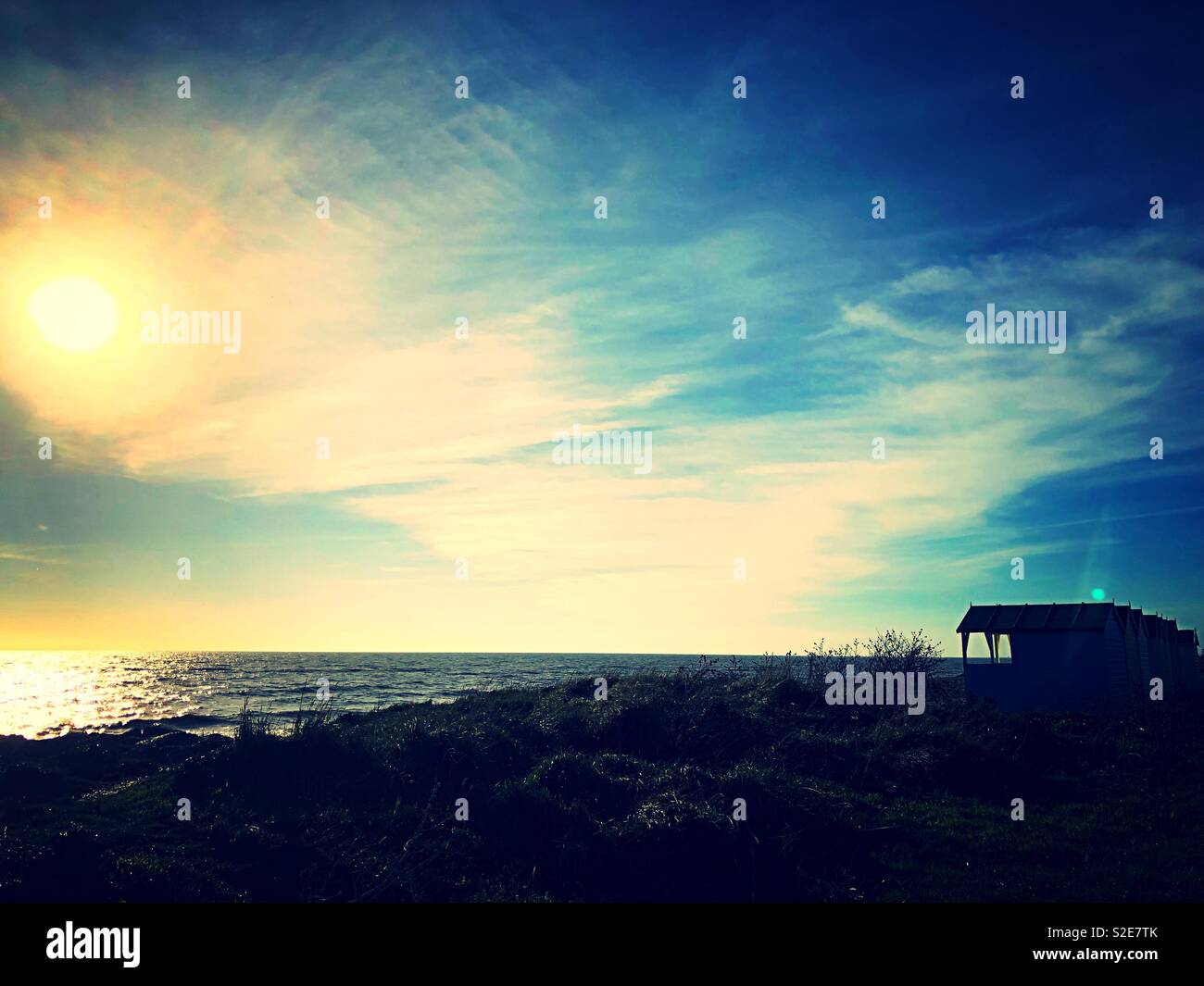 Silhouette of beach huts against low autumn sun on Rustington beach - Smartphone Captured Stock Image