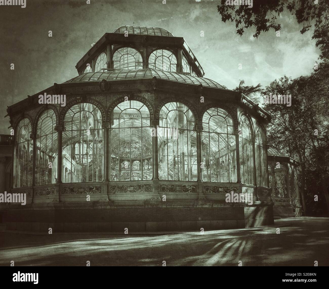 An antique and retro effect image of the famous Palacio de Cristal (Crystal Palace) in Beun Retiro Park in Madrid, Spain. No people present which adds to the spooky or sinister effect. Photo © -CH. - Smartphone Captured Stock Image