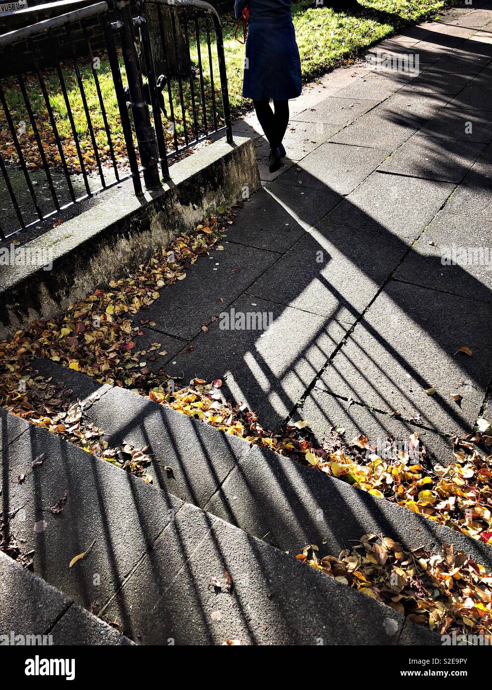 Woman walking on a sunny day in autumn Dumfries town centre, Scotland, with shadows visible from the strong sunlight. - Smartphone Captured Stock Image