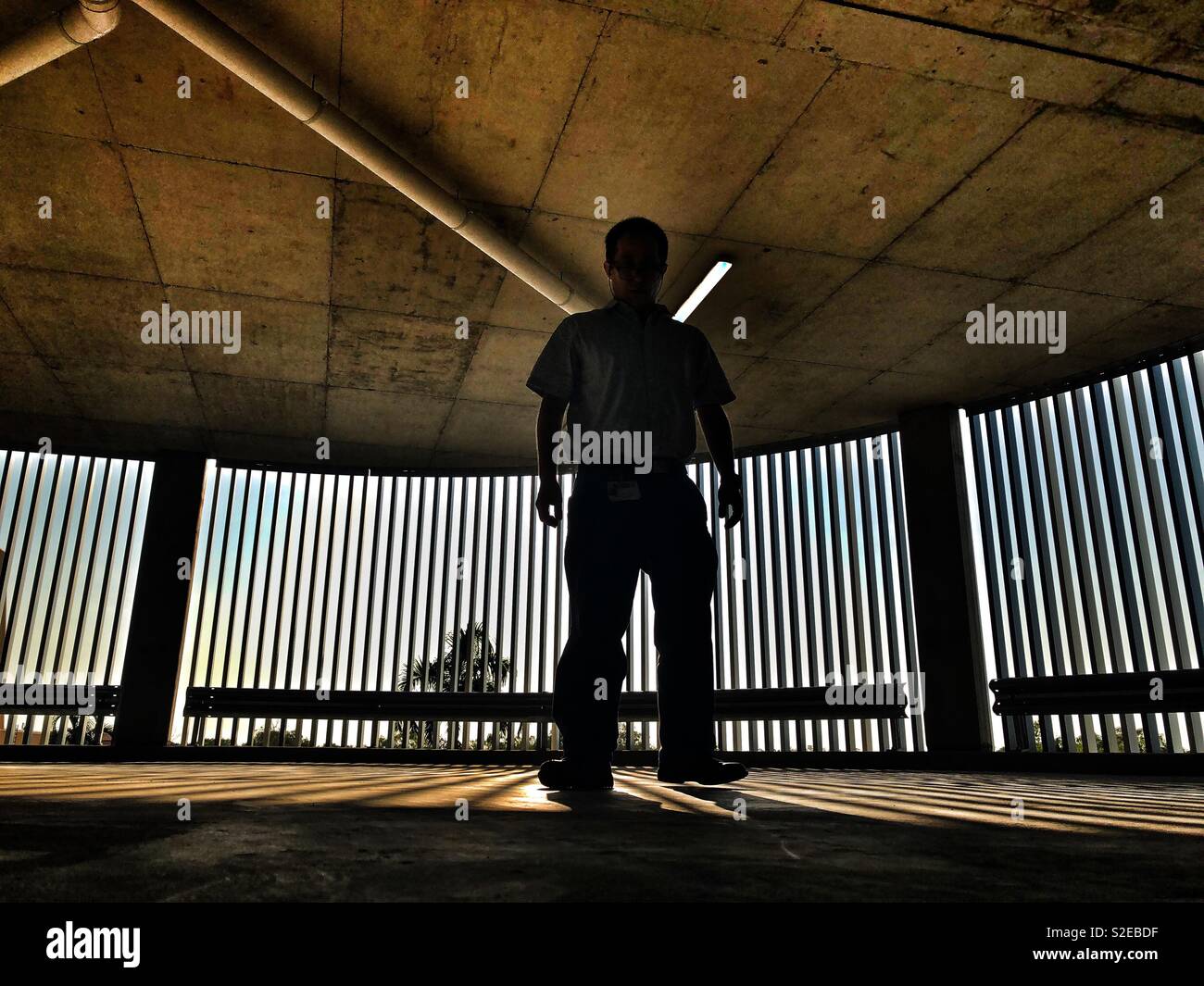 Backlighted man in an undercover empty parking lot. - Smartphone Captured Stock Image Backlighted man in an undercover empty parking lot. - Smartphone Captured Stock Image