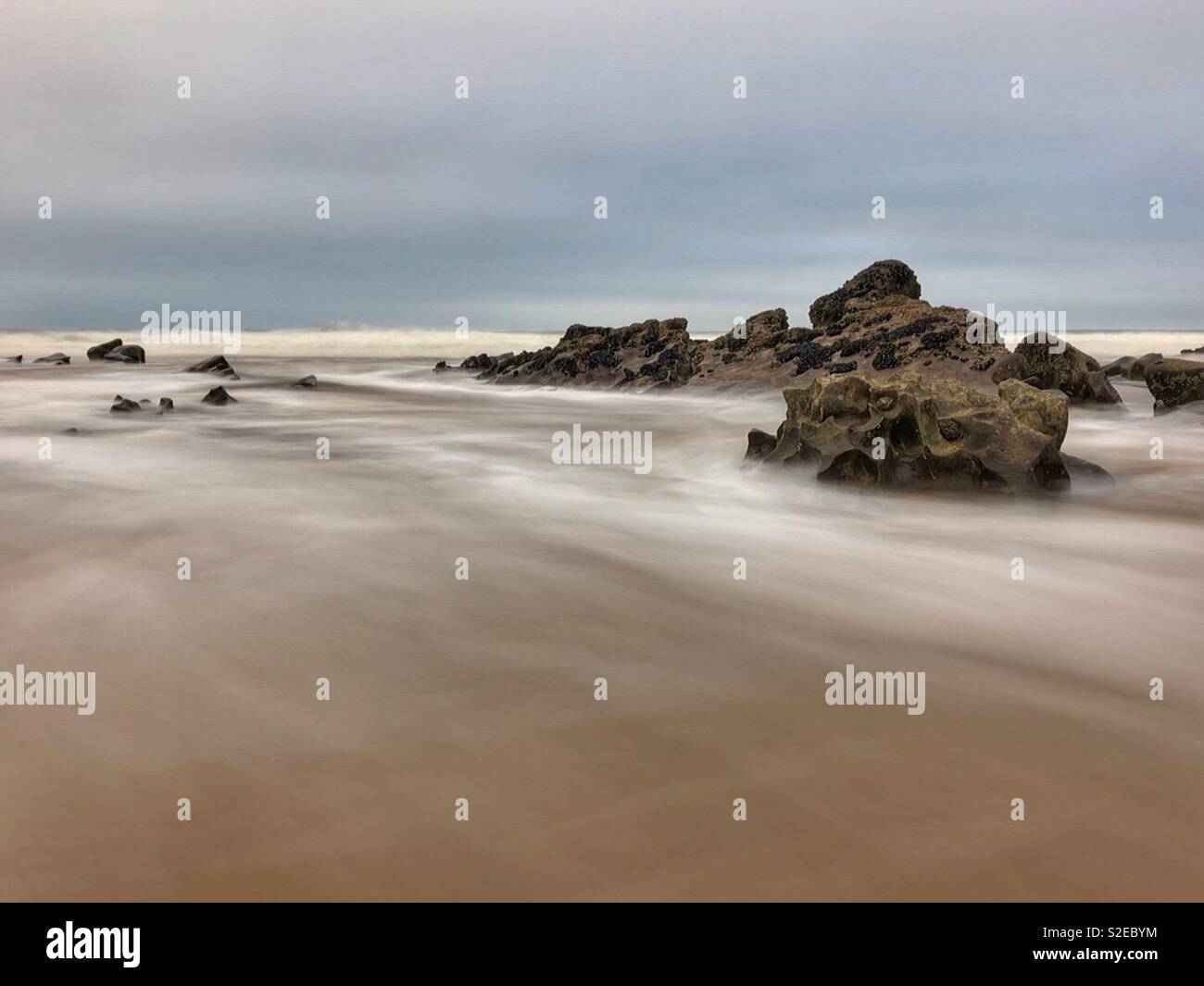 Incoming tide washing around rocks, Gower, Wales, November. - Smartphone Captured Stock Image