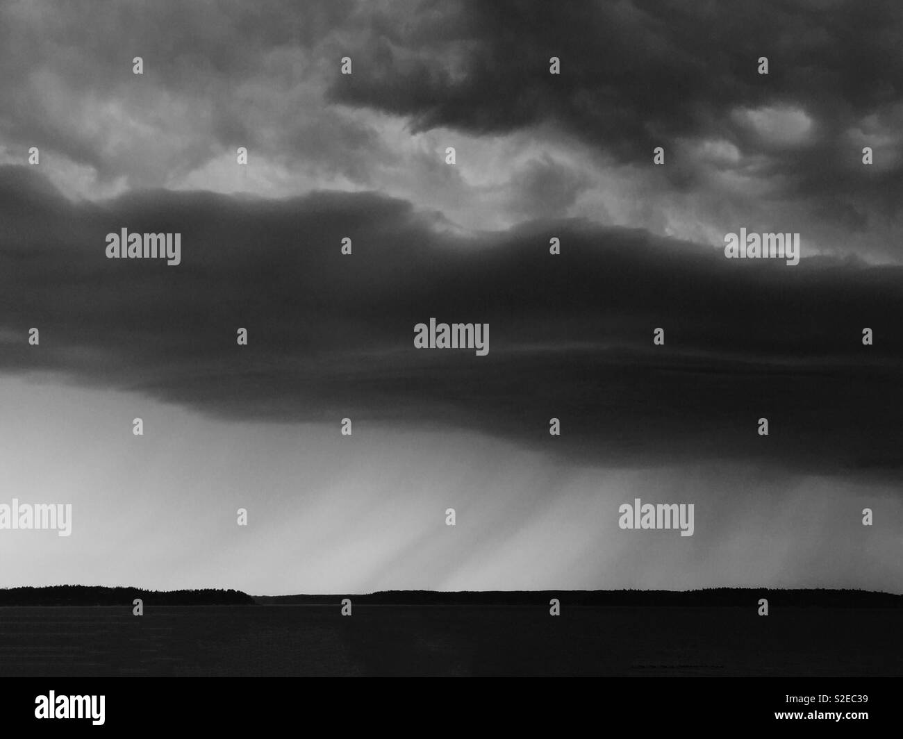 Dramatic clouds and whisps of rain in a monochromatic landscape Stock Photo